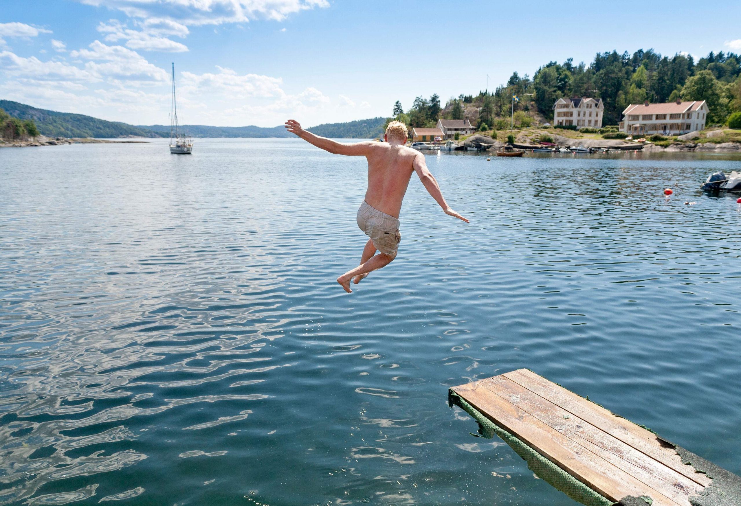 A man jumping into the sea from a wooden diving board.