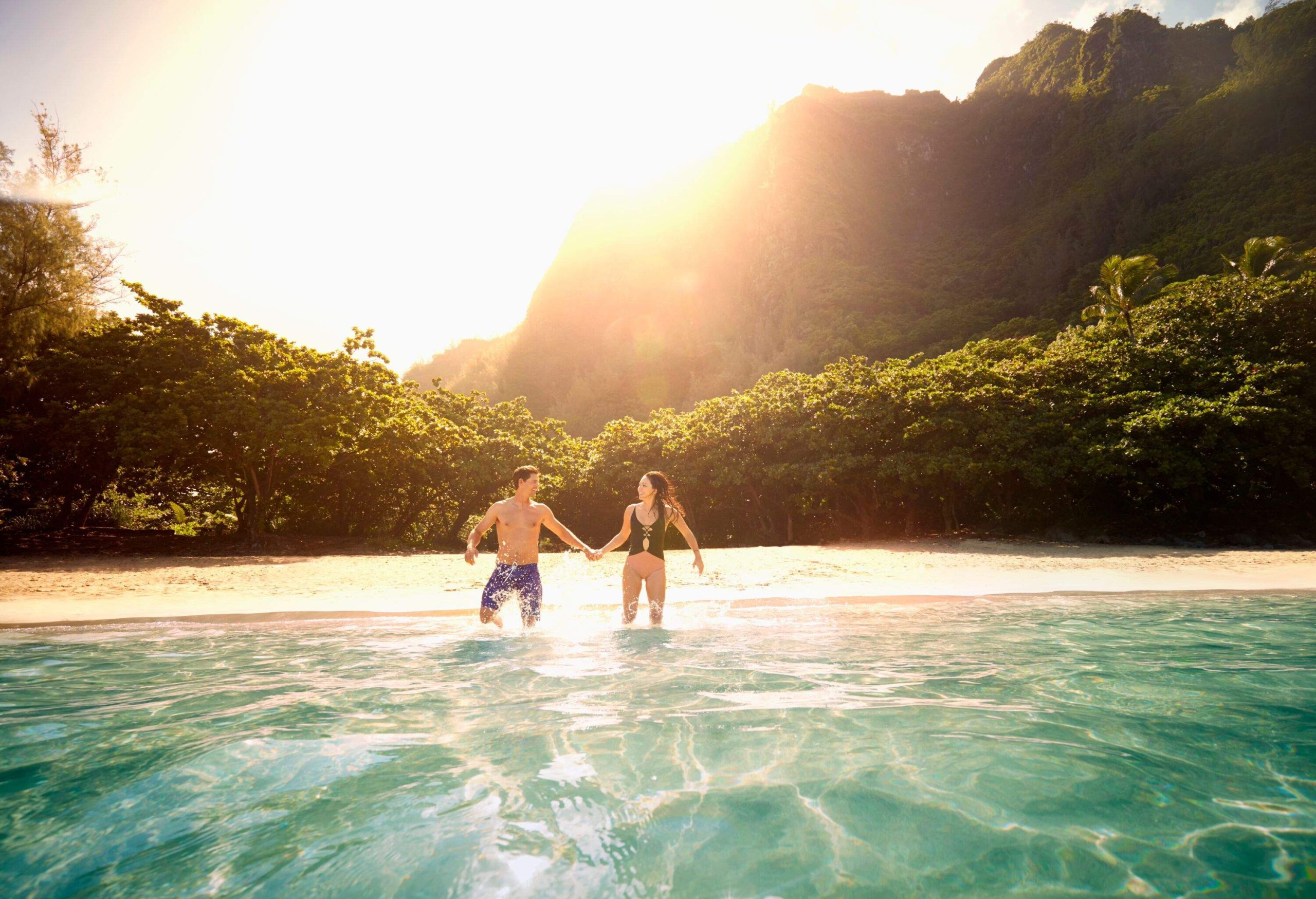 a man and a woman about to go in the water at a tropical beach