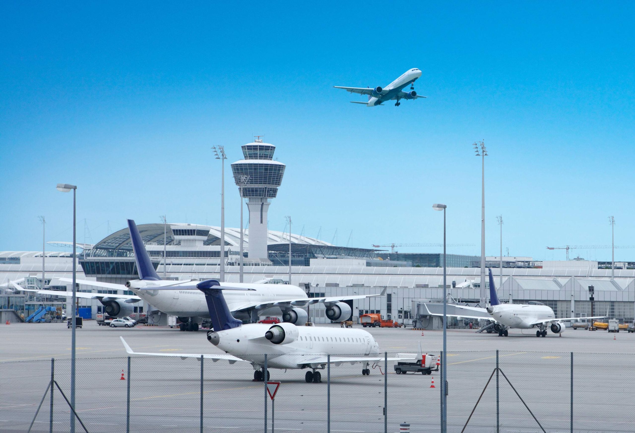 A plane flying over an airport into the clear sky.