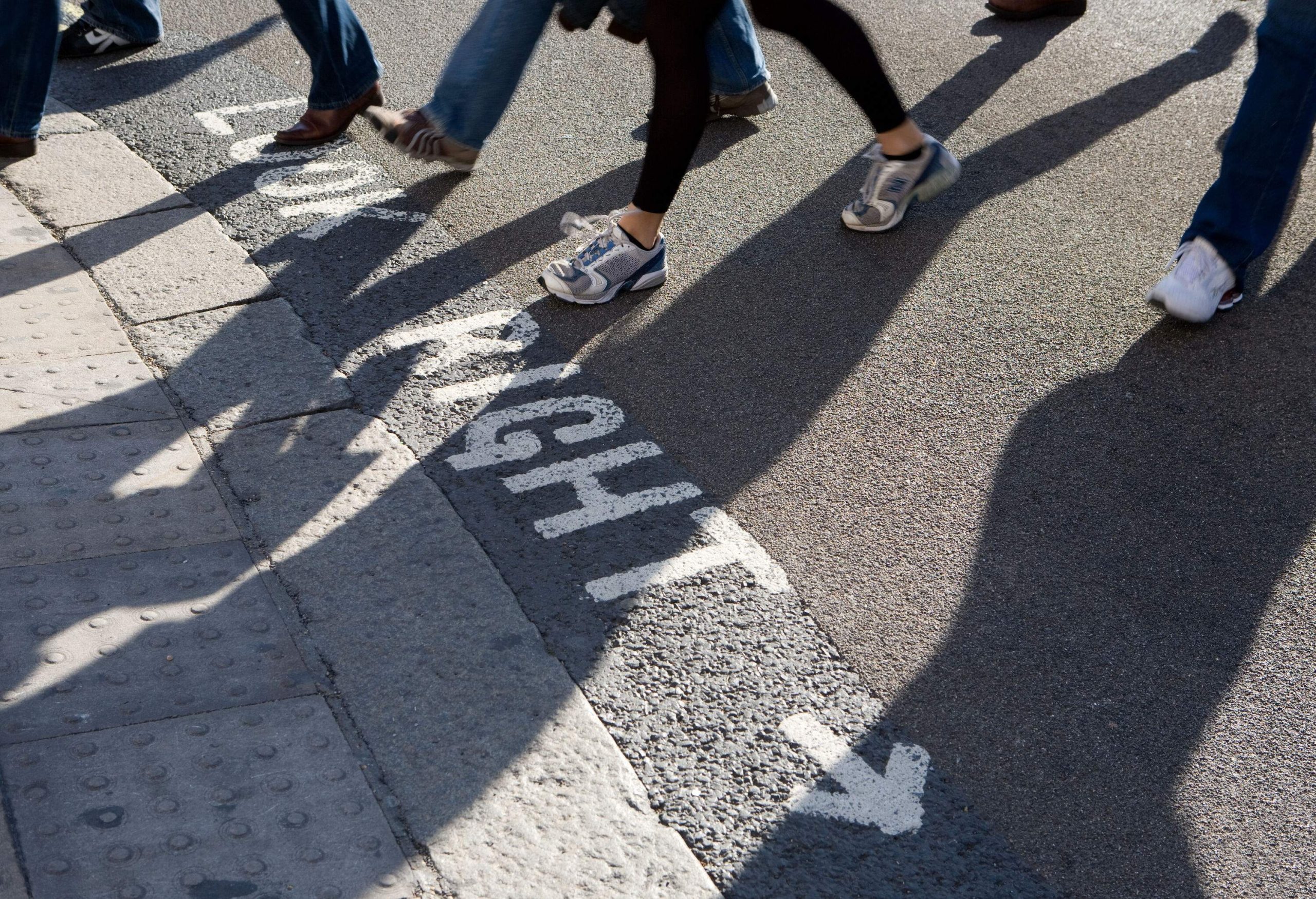 Close-up of people's feet as they cross the pedestrian.
