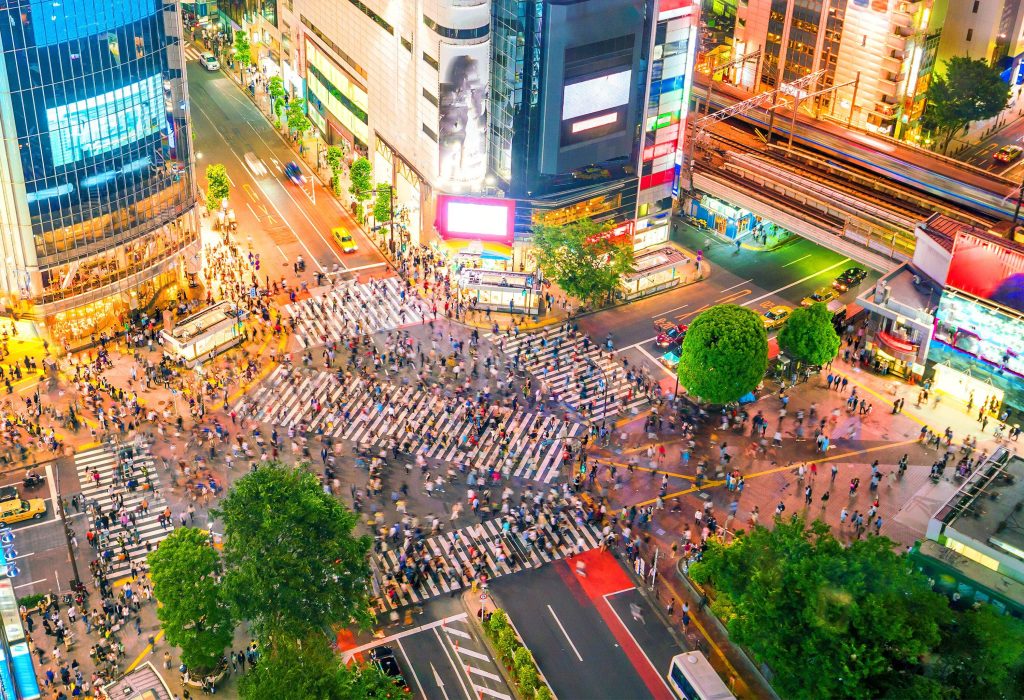 The iconic Shibuya Crossing, with the mesmerising sight of modern buildings towering over a bustling sea of people.