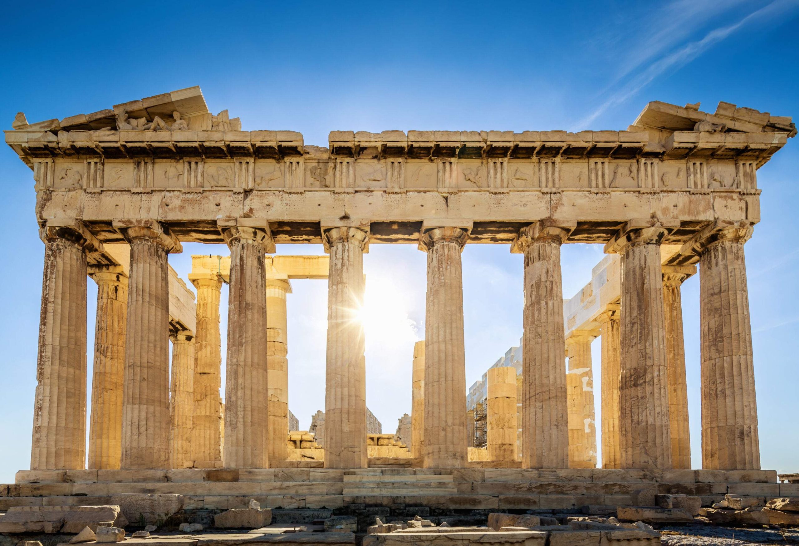 Ruined temple of Parthenon with the sun shining through the columns.