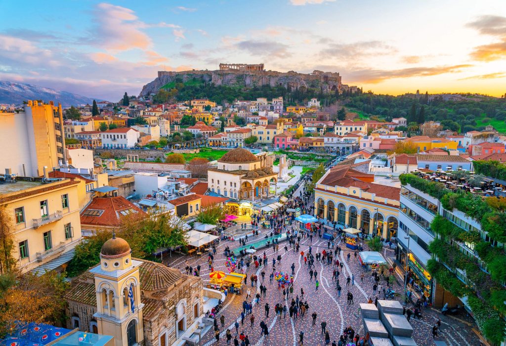Panoramic view of a colourful Mediterranean town with pedestrians walking through it and old buildings on a hilltop