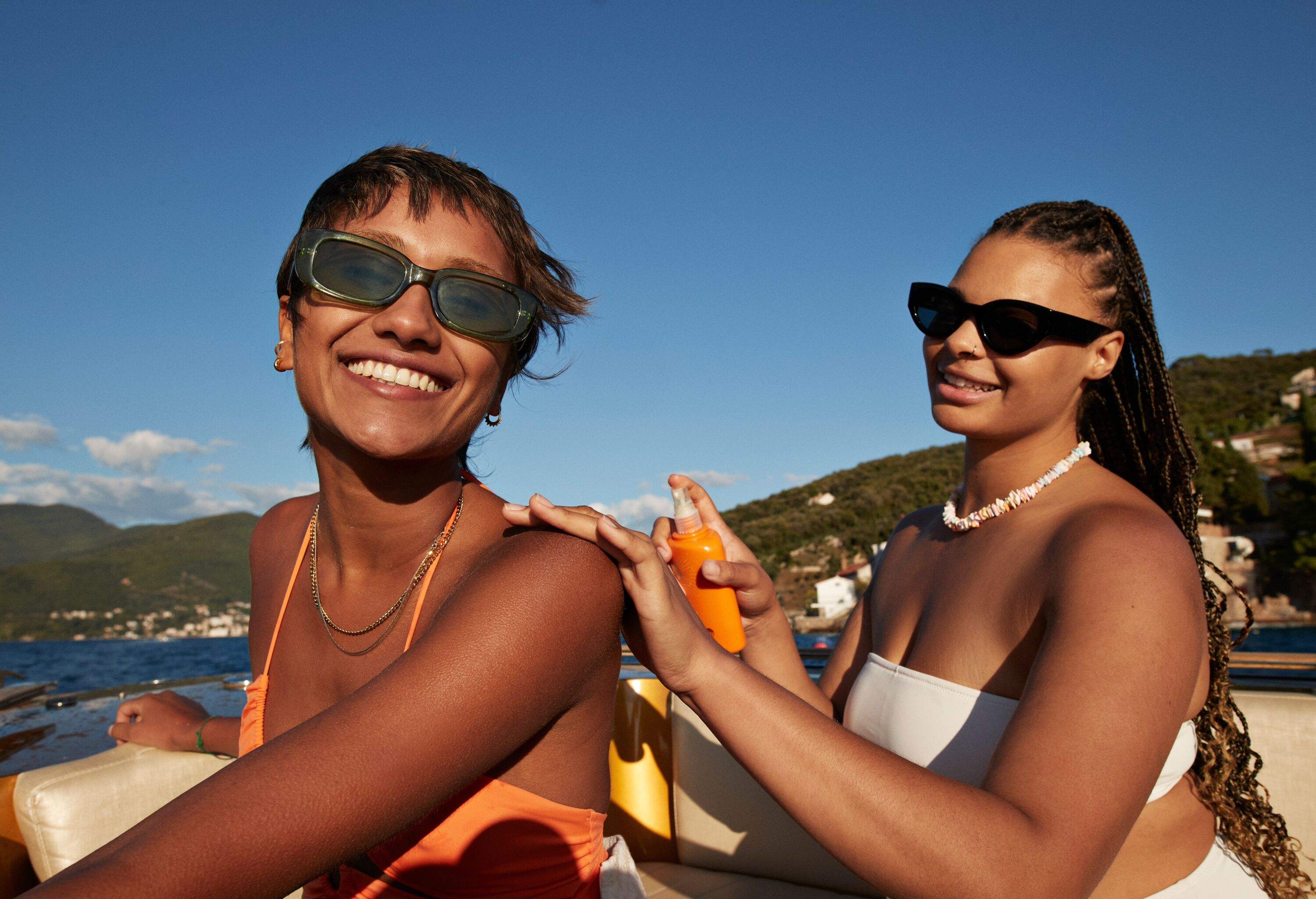 Women sitting on a beach and putting sun lotion on each other
