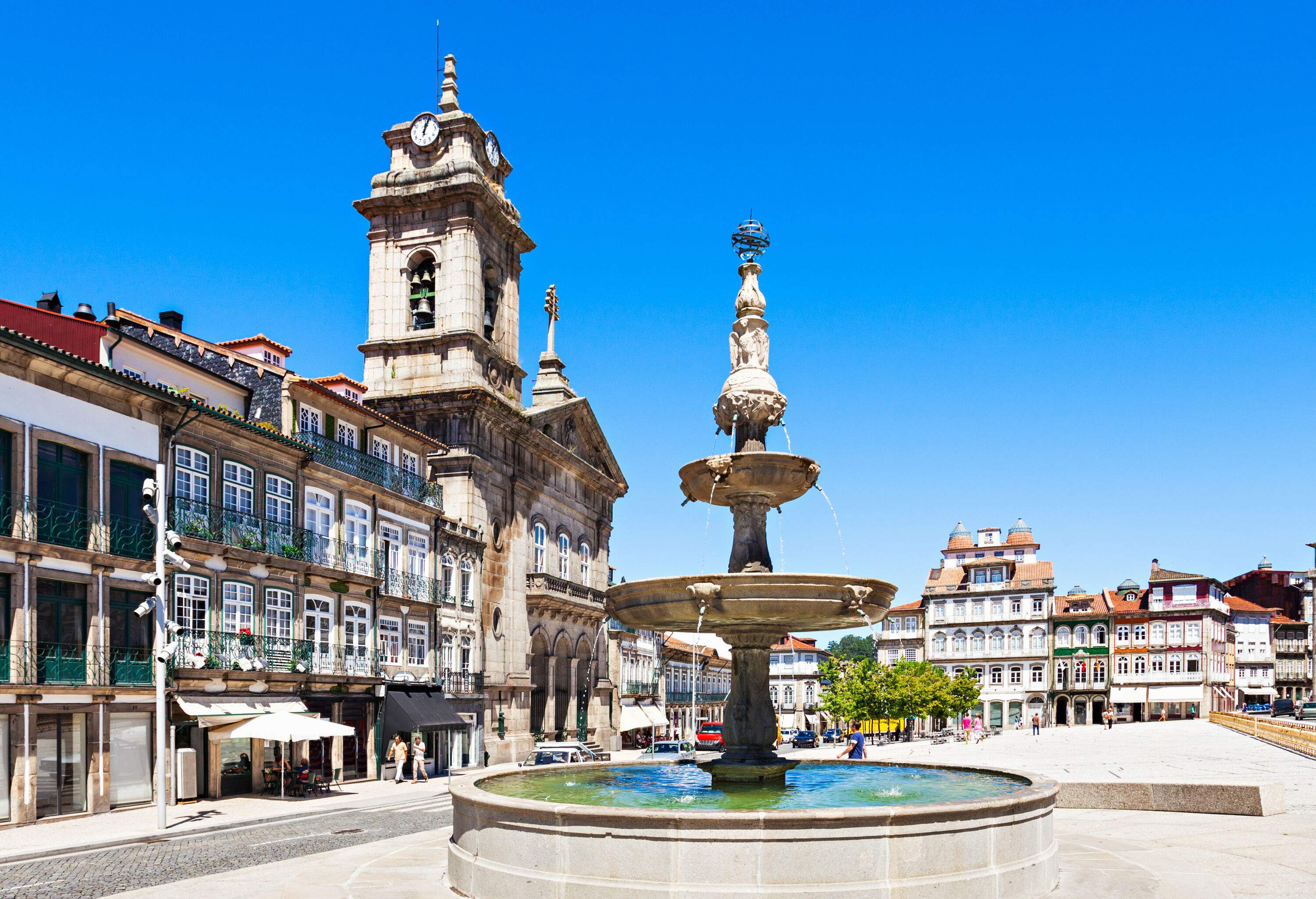 A water fountain in a church square surrounded by historic architecture.