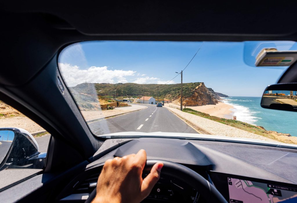 View from car driver's point of view looking at beachside road on a sunny day