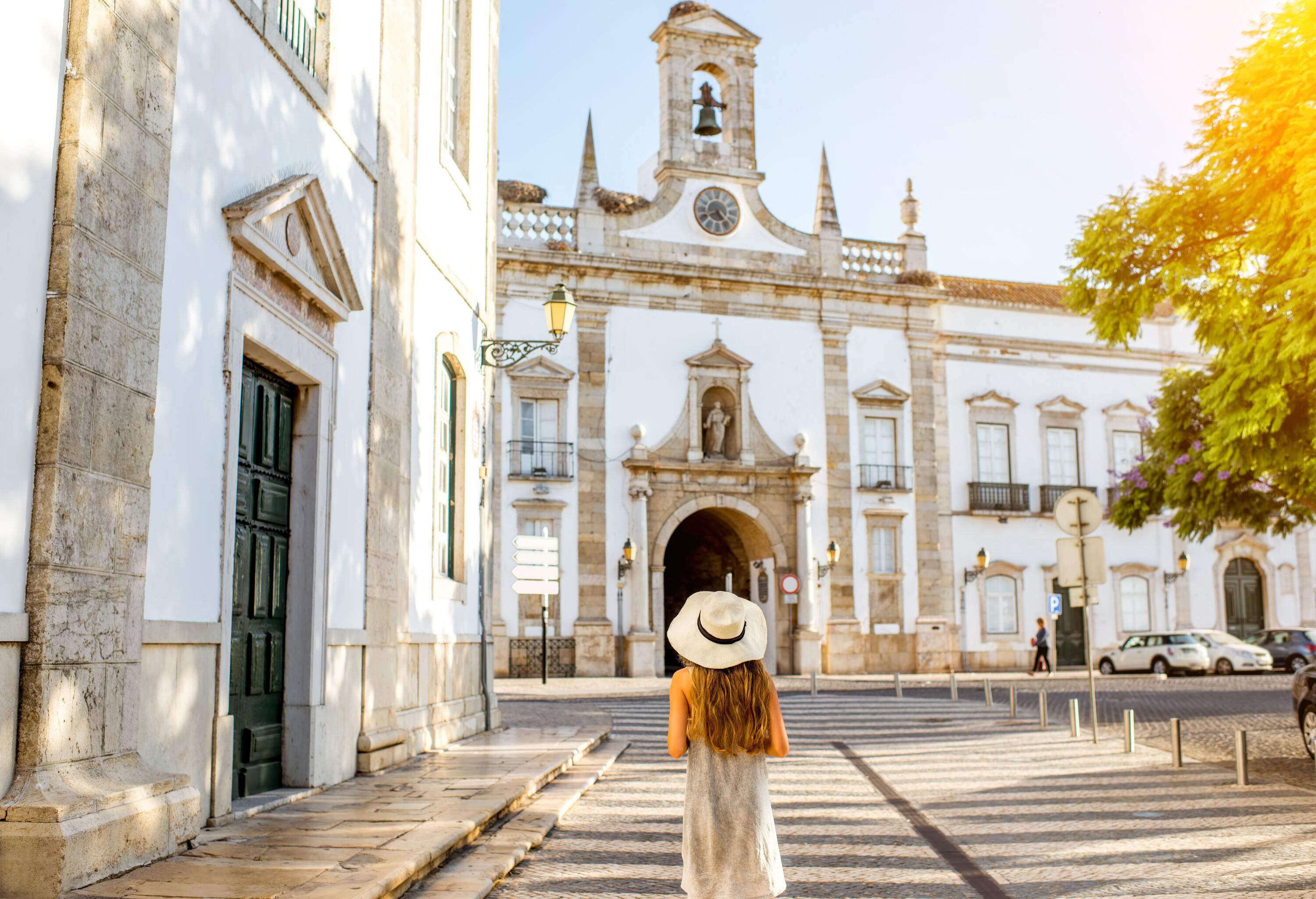 A young tourist stands confidently in front of an ancient church nestled within a city.