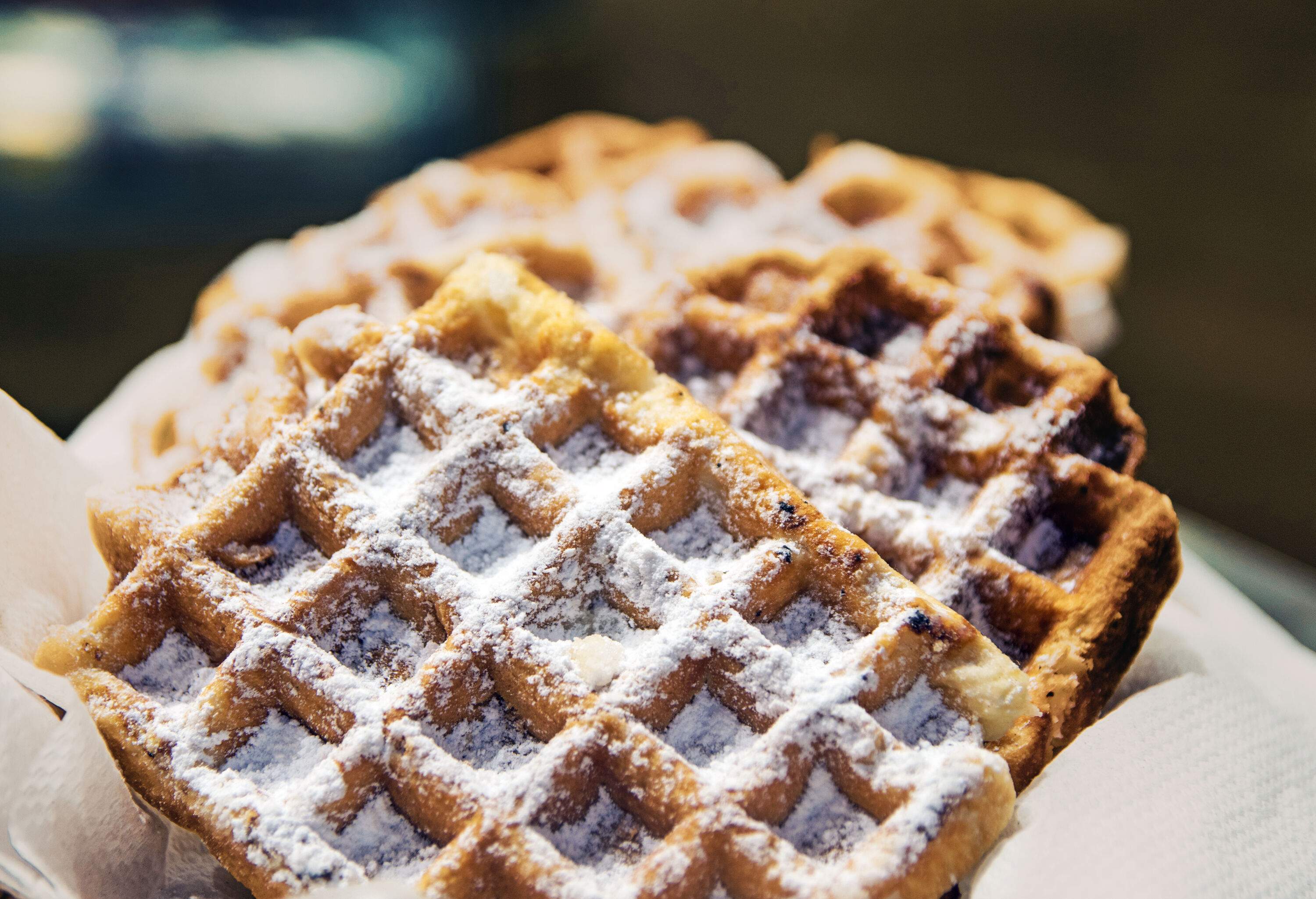 A bunch of waffles sprinkled with powdered sugar.