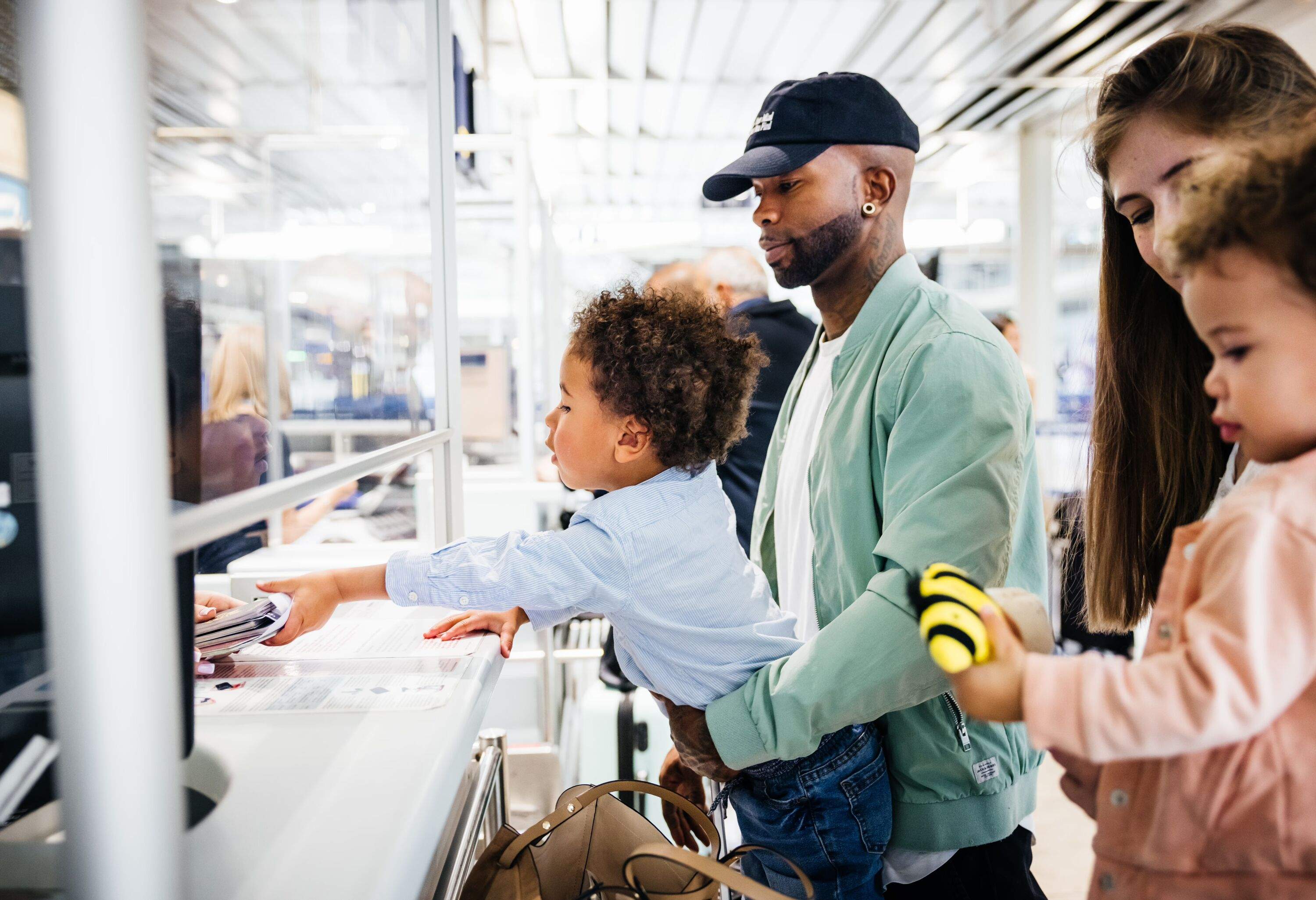 a man and a woman with their two kids in the airport check-in being handed their passports