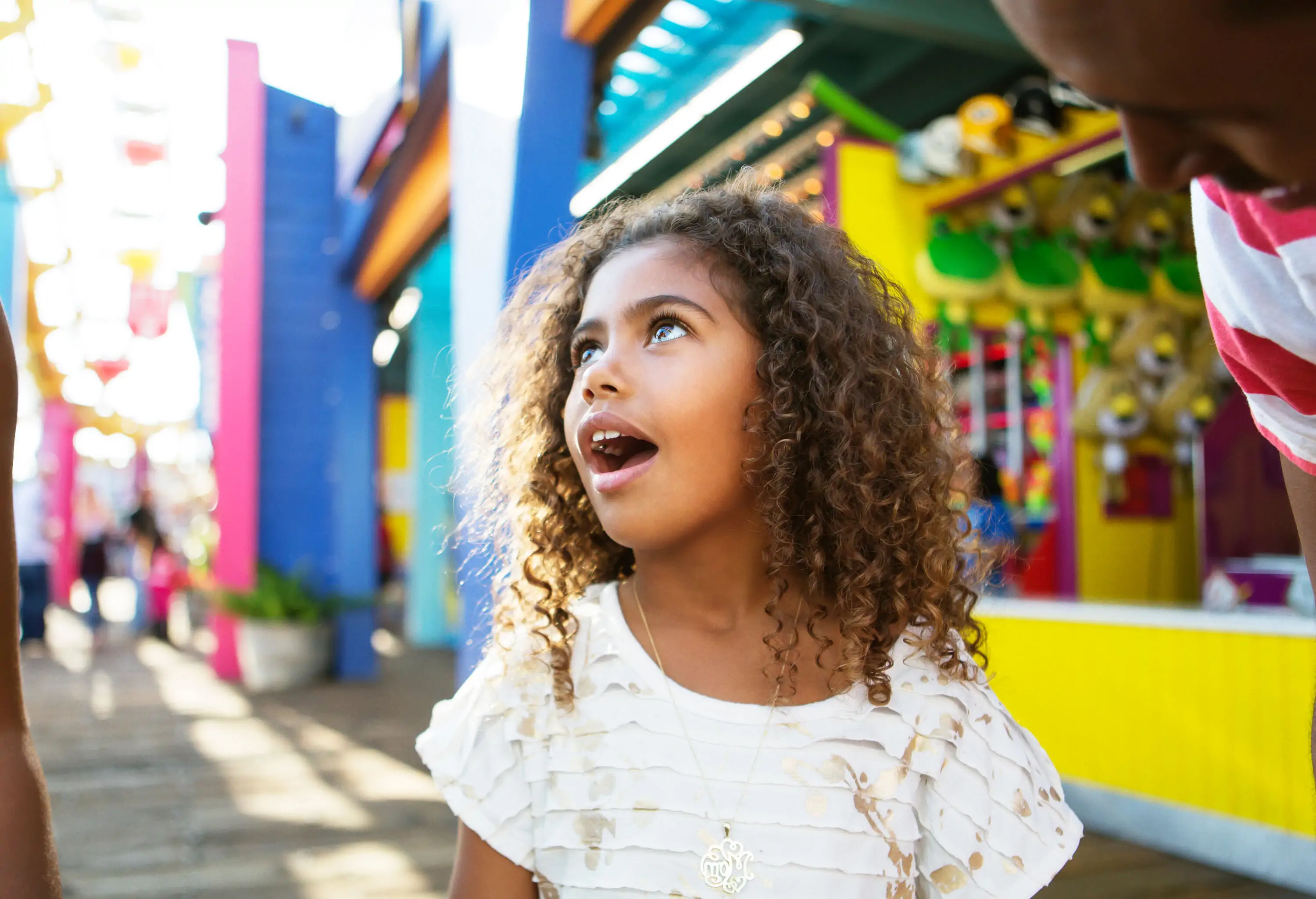 A wide-eyed girl explores an amusement park, her mouth agape in wonder and amusement as she takes in the dazzling sights and thrilling attractions.