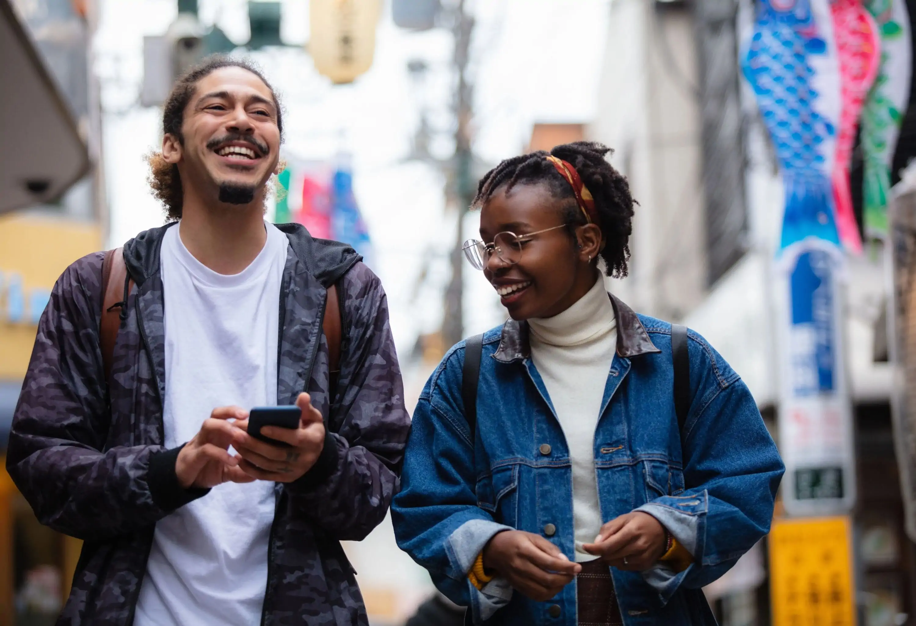 Two people smile as they walk along the sidewalk in Tokyo, Japan.