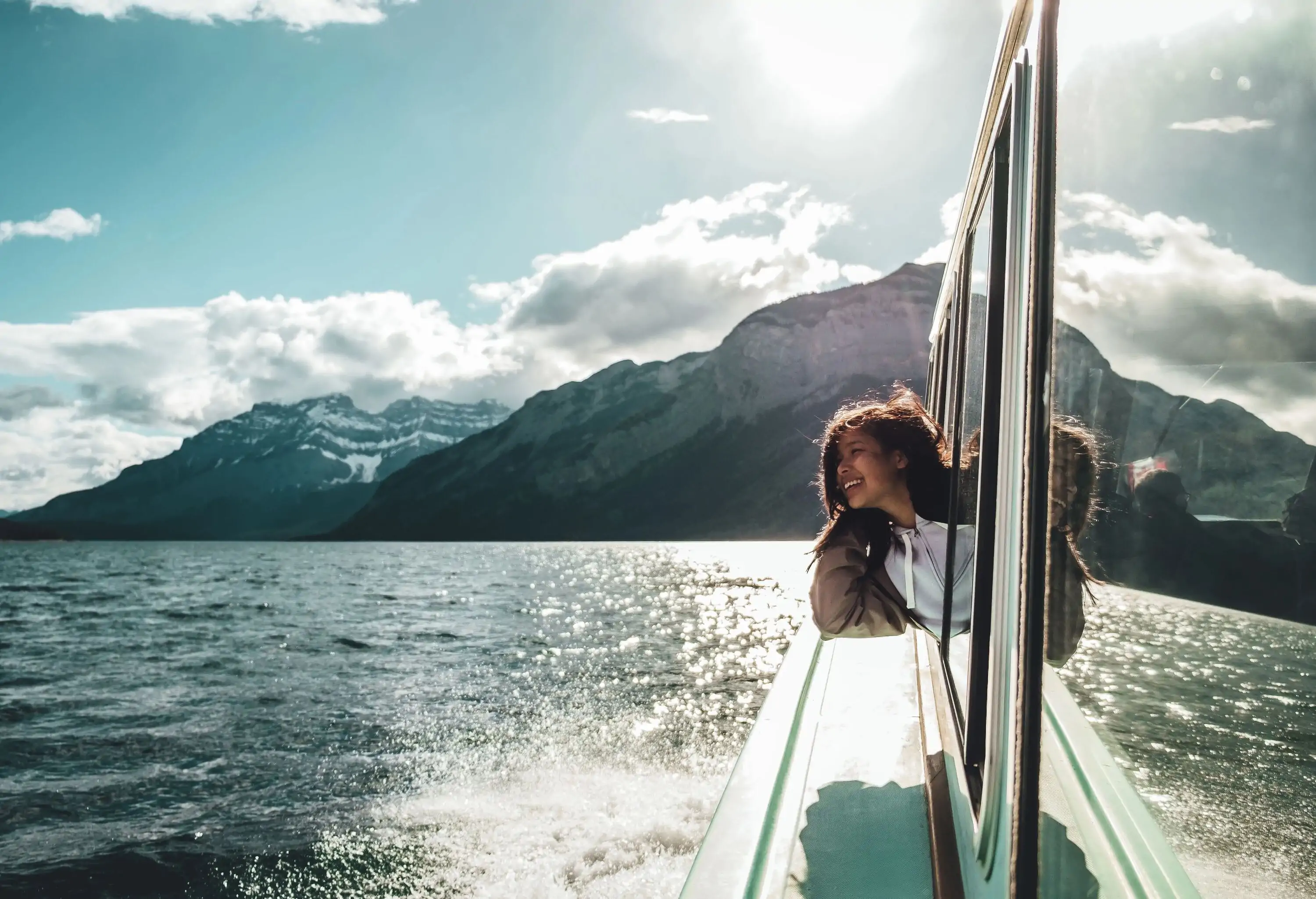Smiling woman on a boat in a lake by mountains