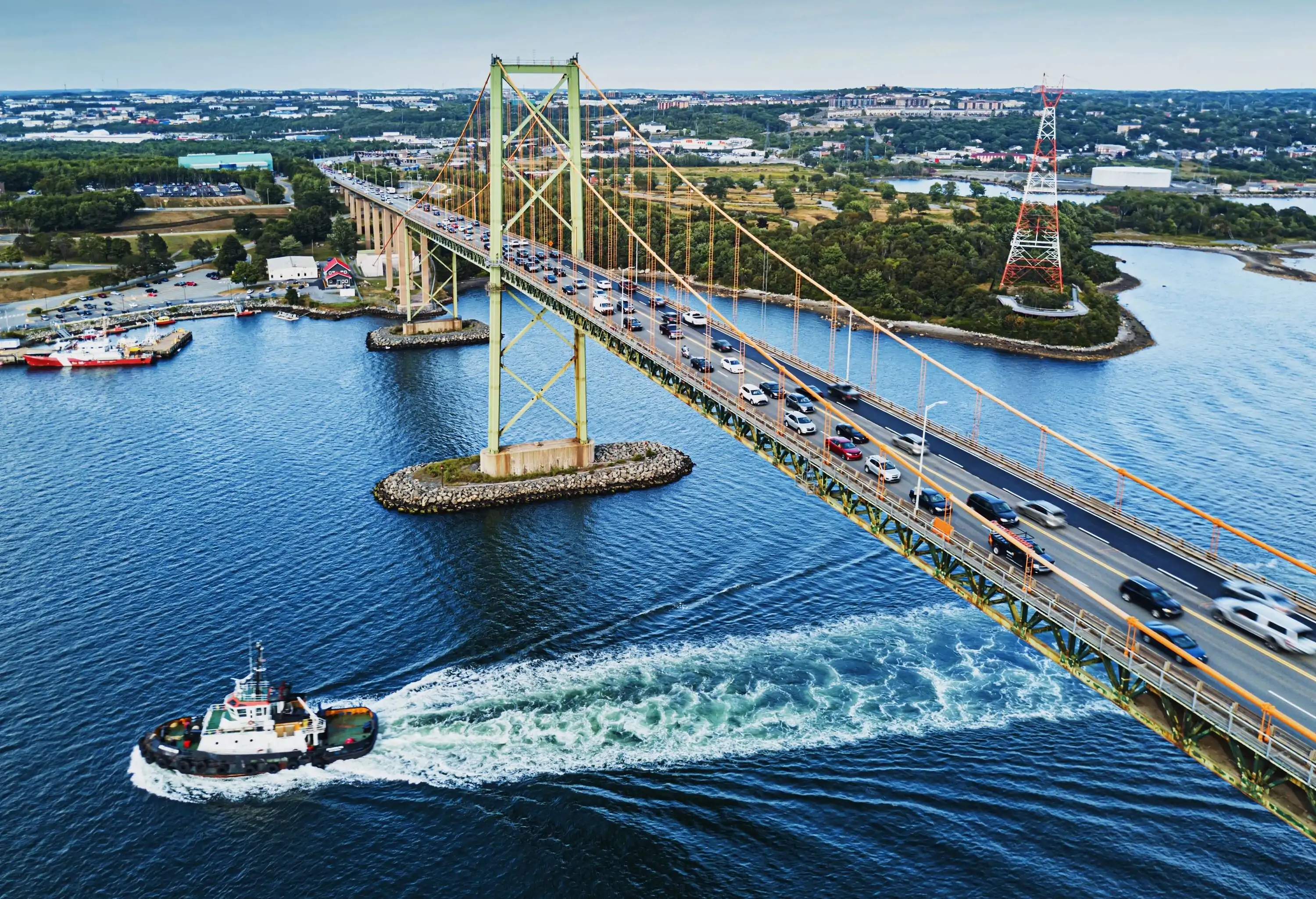 A tugboat beneath rush hour traffic on the MacKay Bridge, Halifax Harbour.