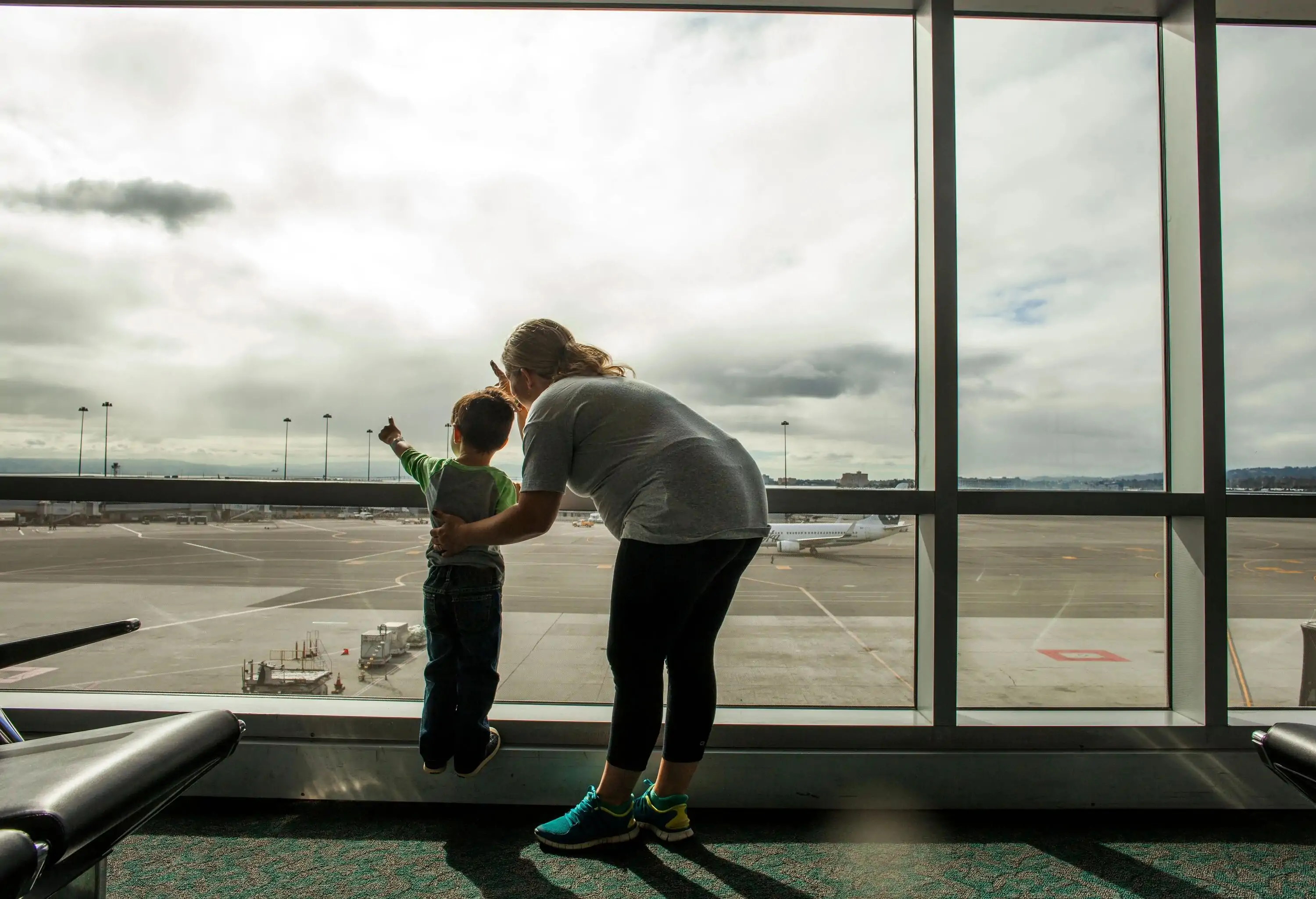 Mother and young child looking out airport window