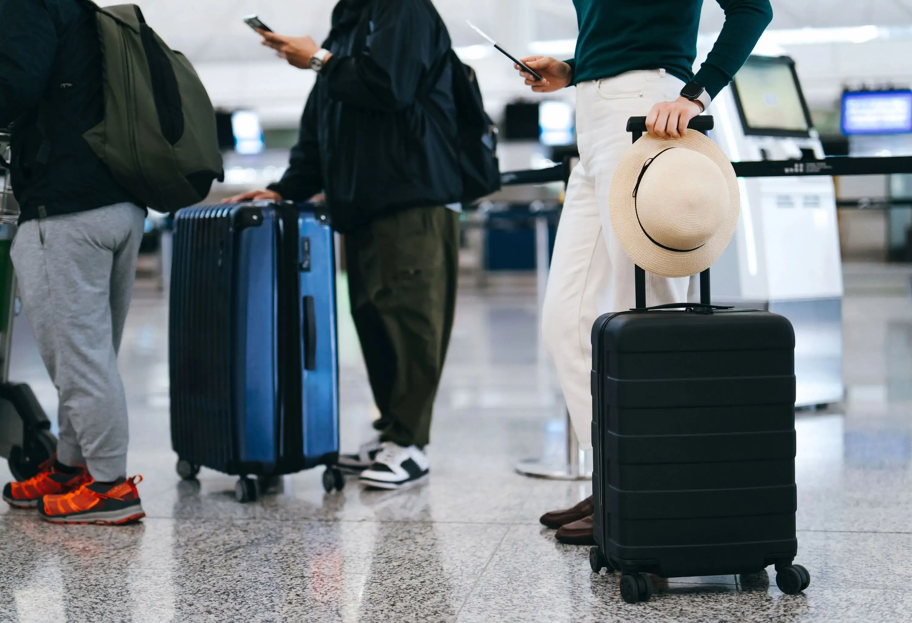 Cropped shot of group of airline passengers with suitcases standing in queue, waiting at check-in counter at International airport. Ready for a trip. Business travel. Travel and vacation concept