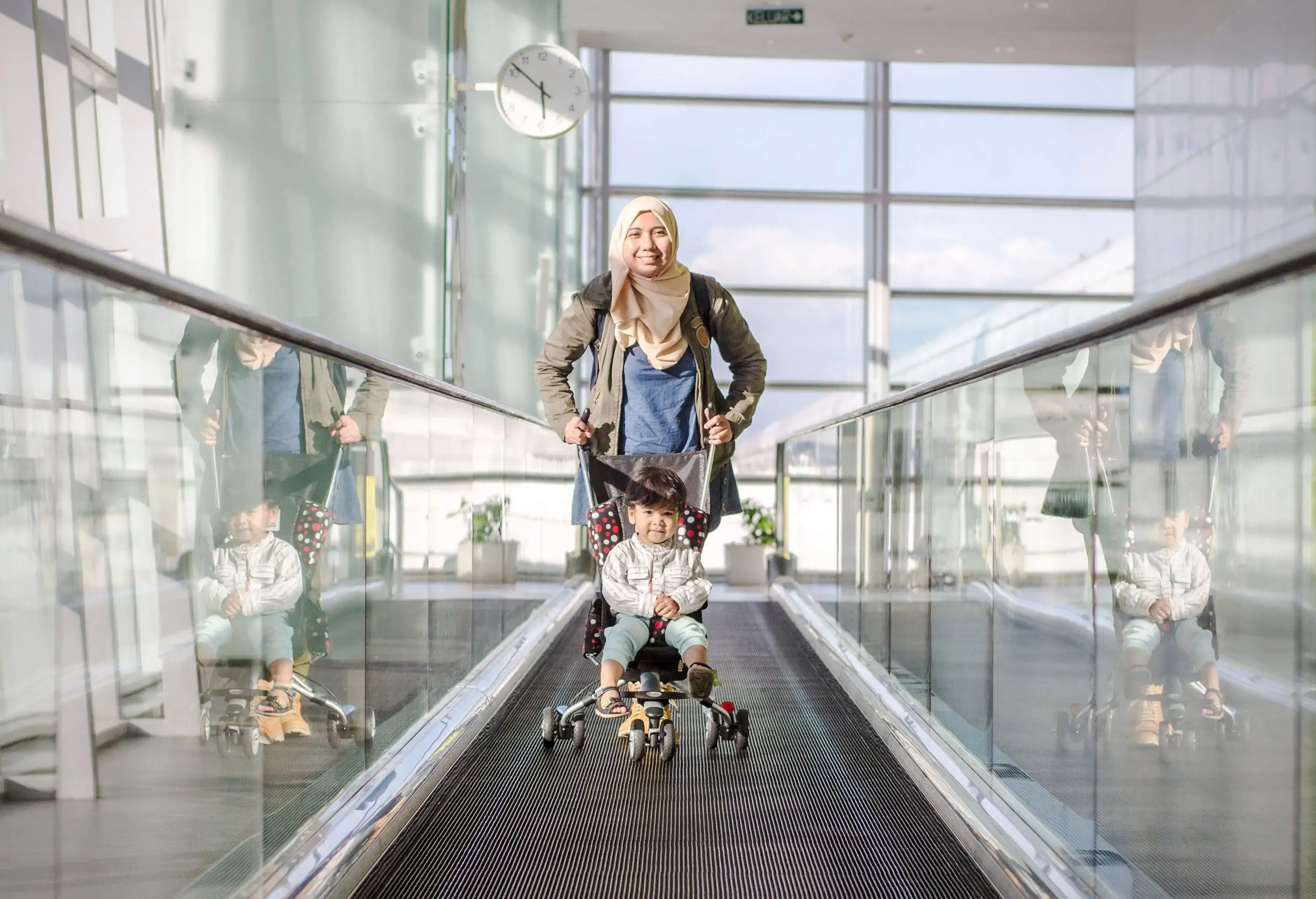 A woman pushing a stroller on a fast lane at the airport