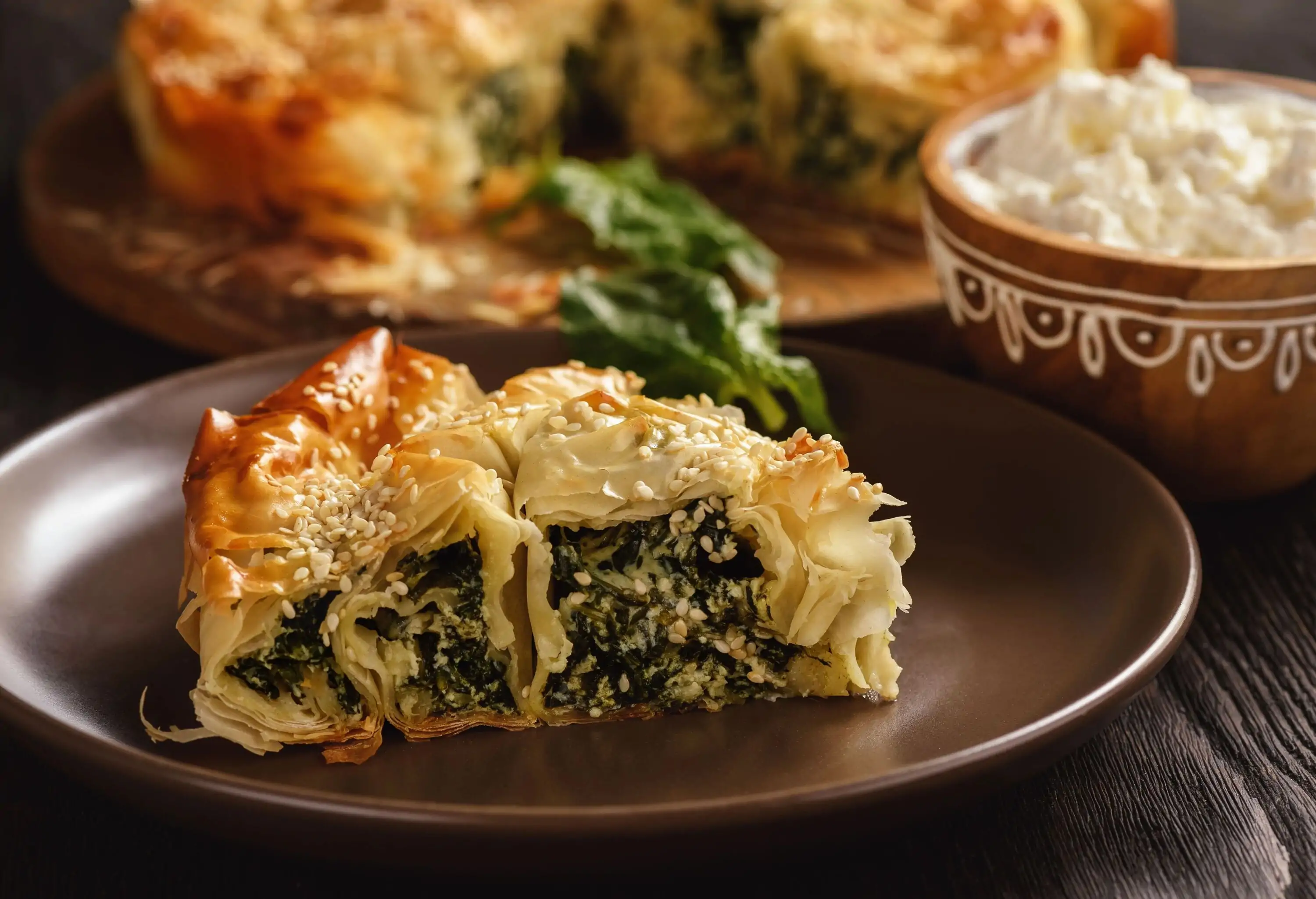 A savory Albanian spinach pie on a round brown plate.