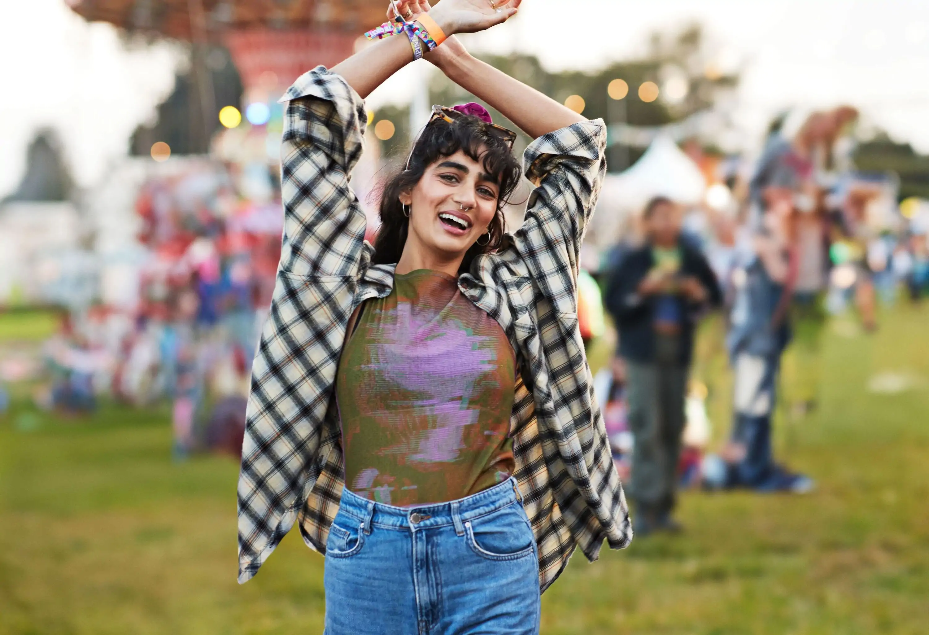 Portrait of cheerful woman dancing with arms raised at music festival during sunset