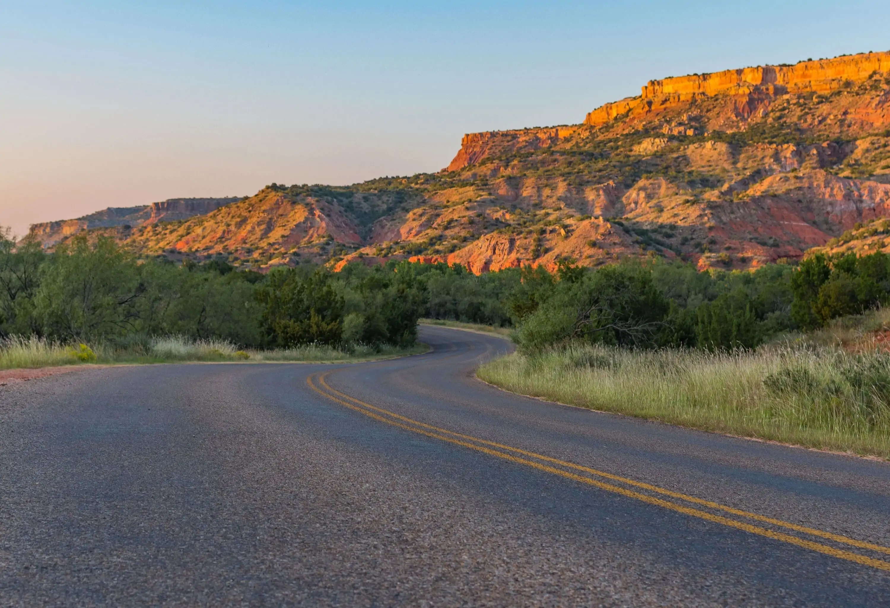 A winding roadway surrounded by sandstone hills and mountains.