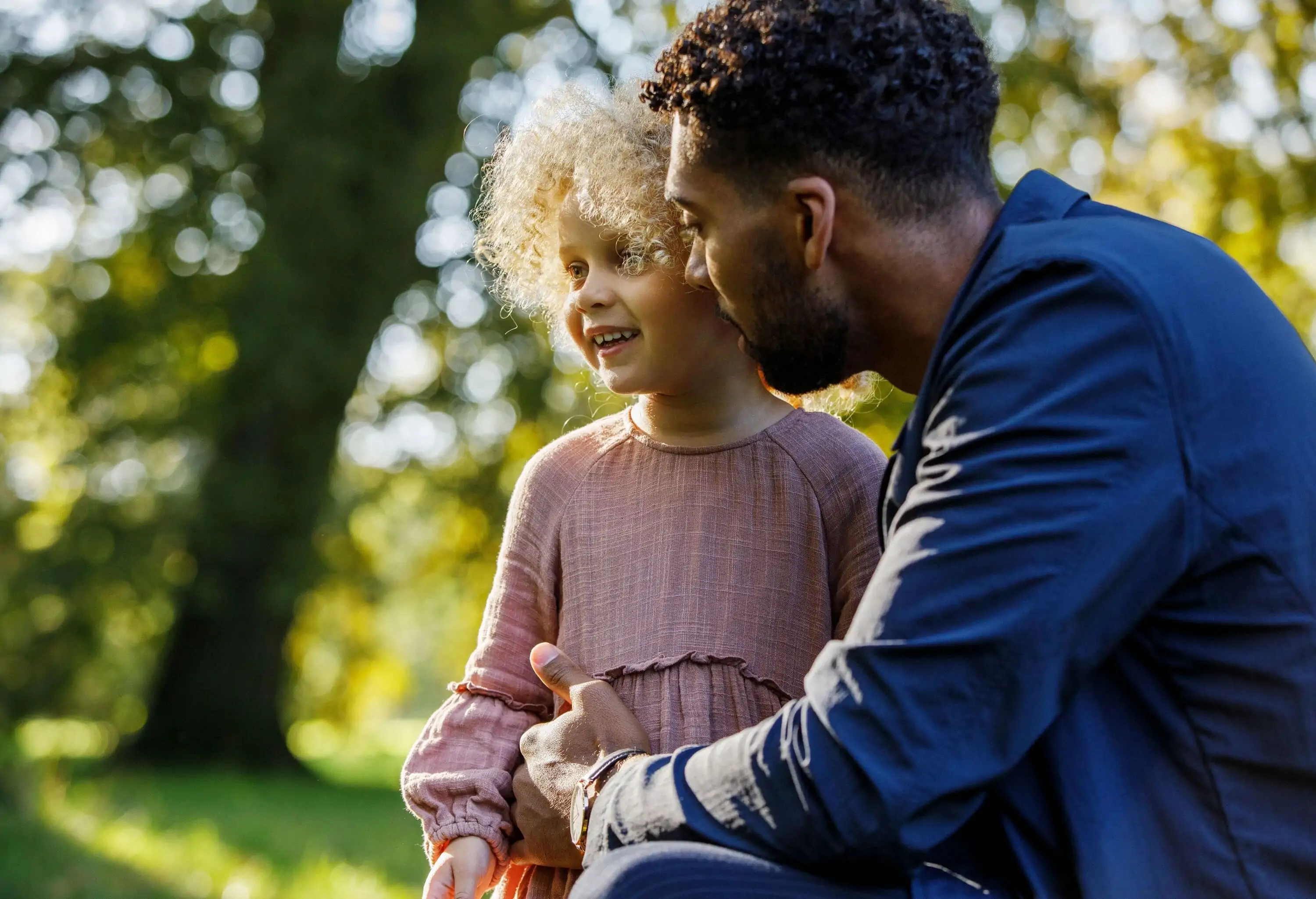 A father with his beautiful blonde afro daughter in the park.