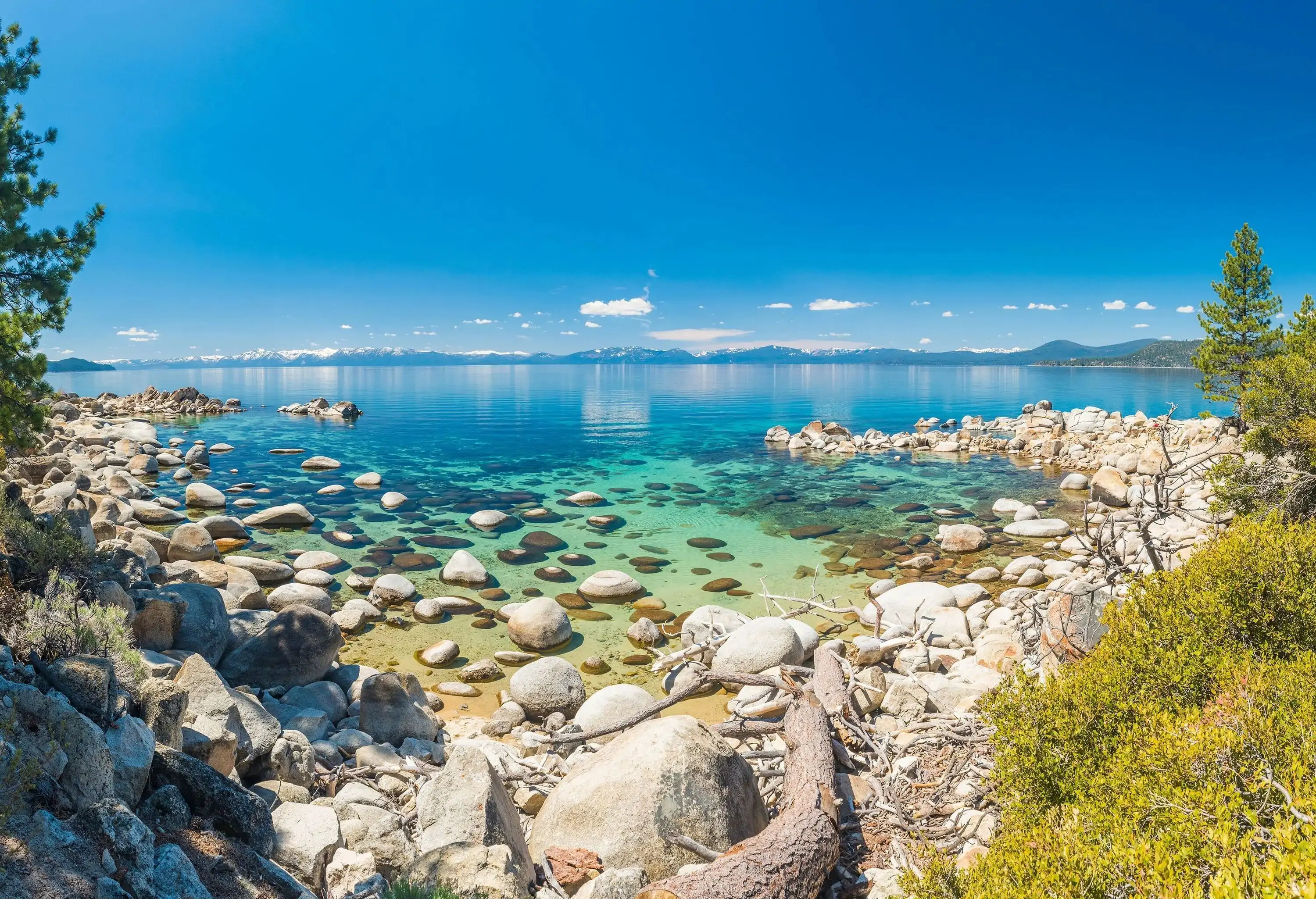 A low wall of rocks curving around the shore of a sky-blue lake.