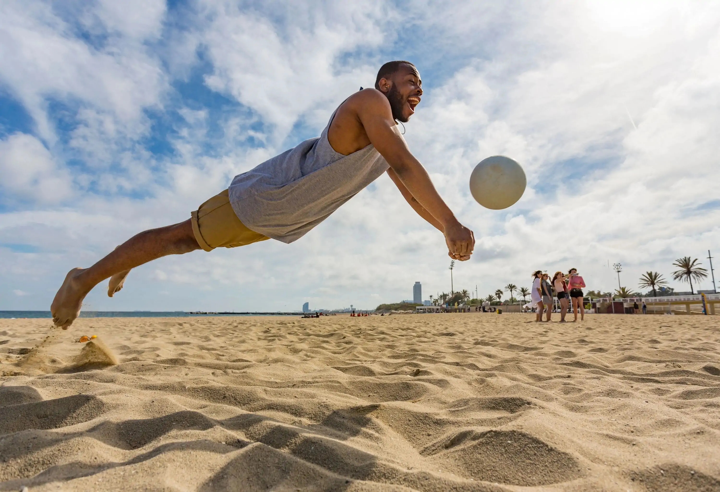 A beach volleyball player diving for the ball in action.
