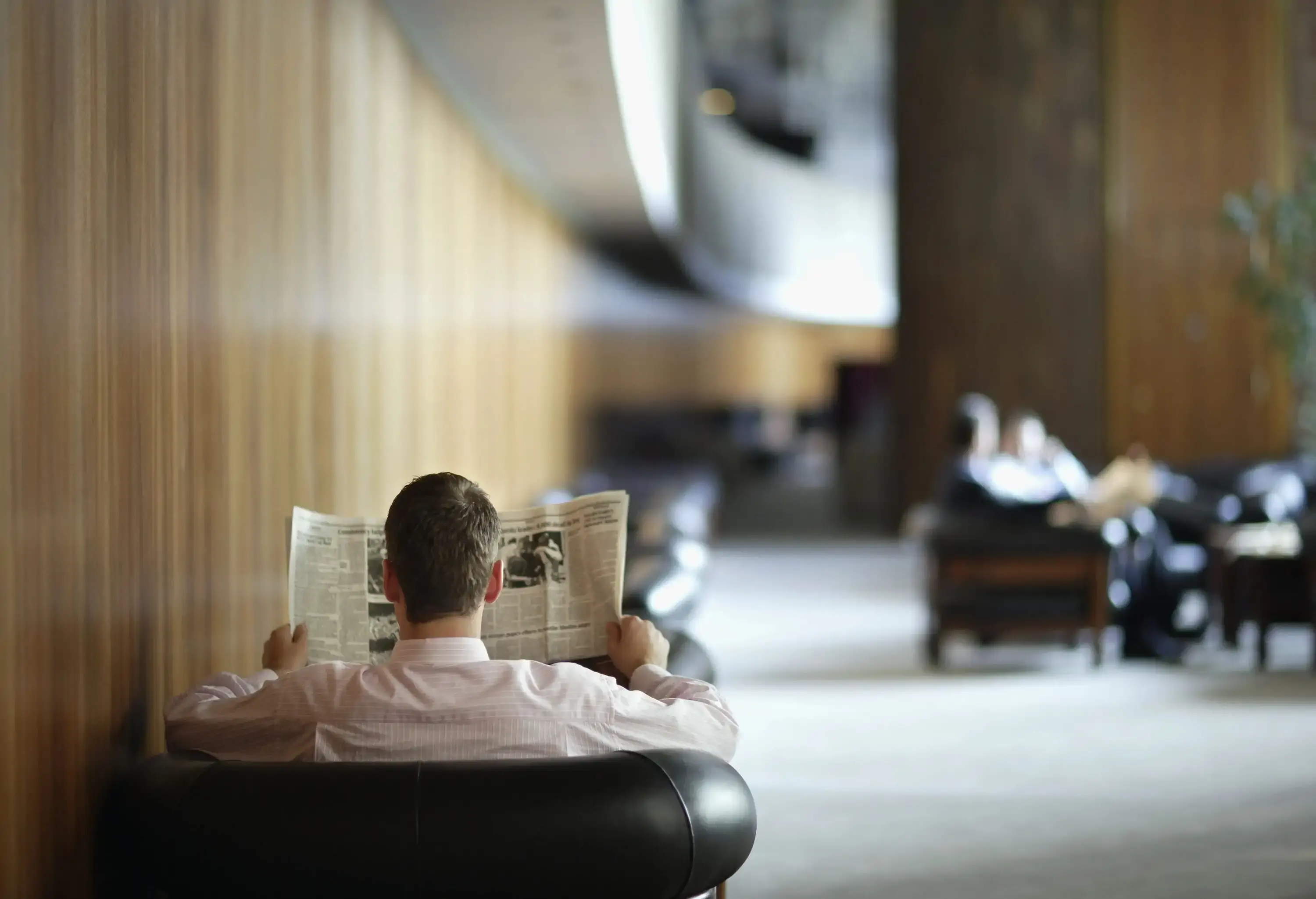 A man sitting in a hotel lobby reading a newspaper
