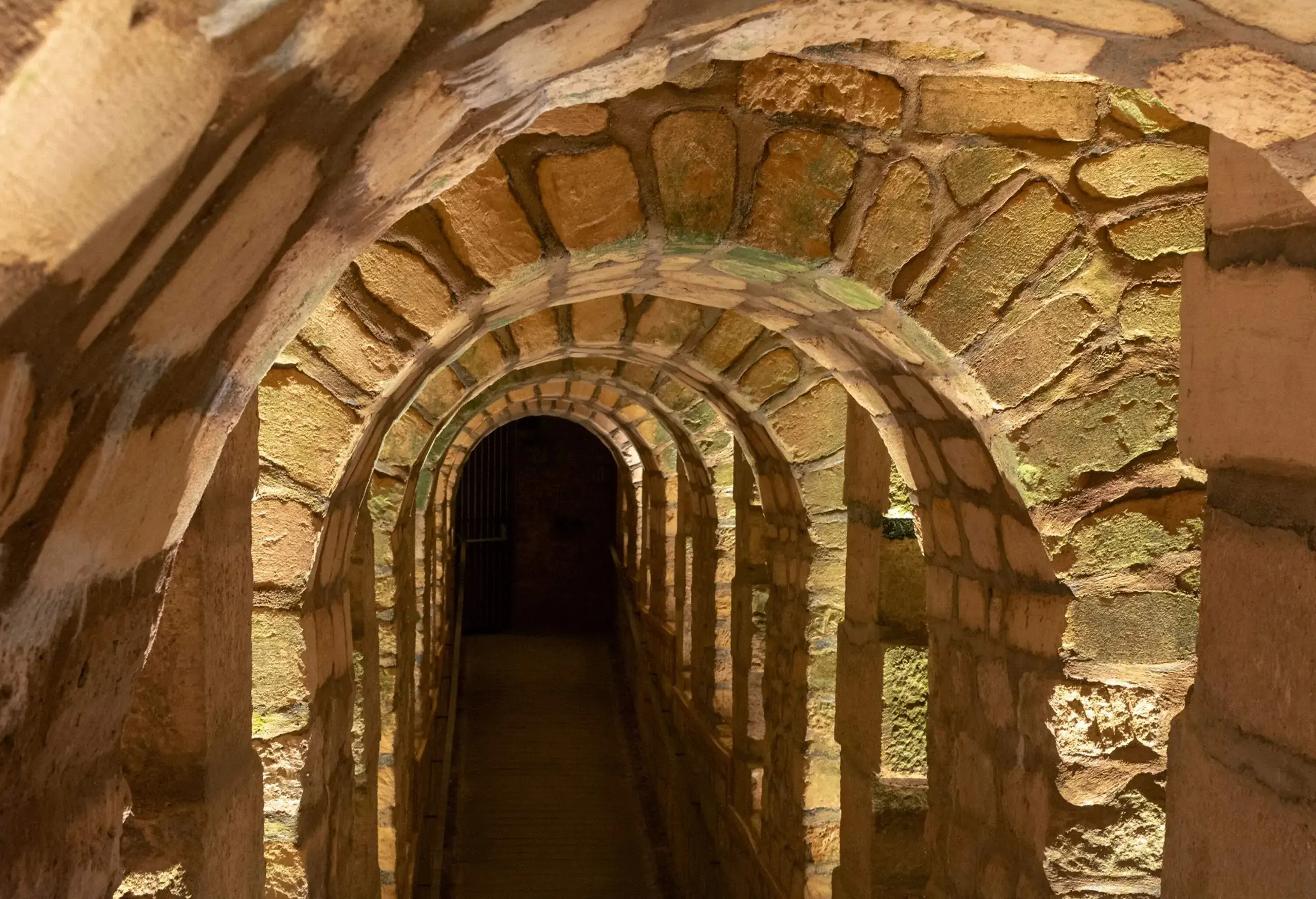 A row of stone arches in a tunnel inside a catacombs.