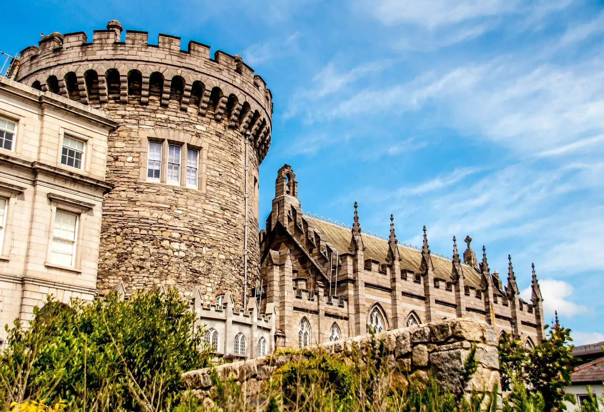 A historic fortress medieval castle with a round tower adjacent to a gothic revival chapel.