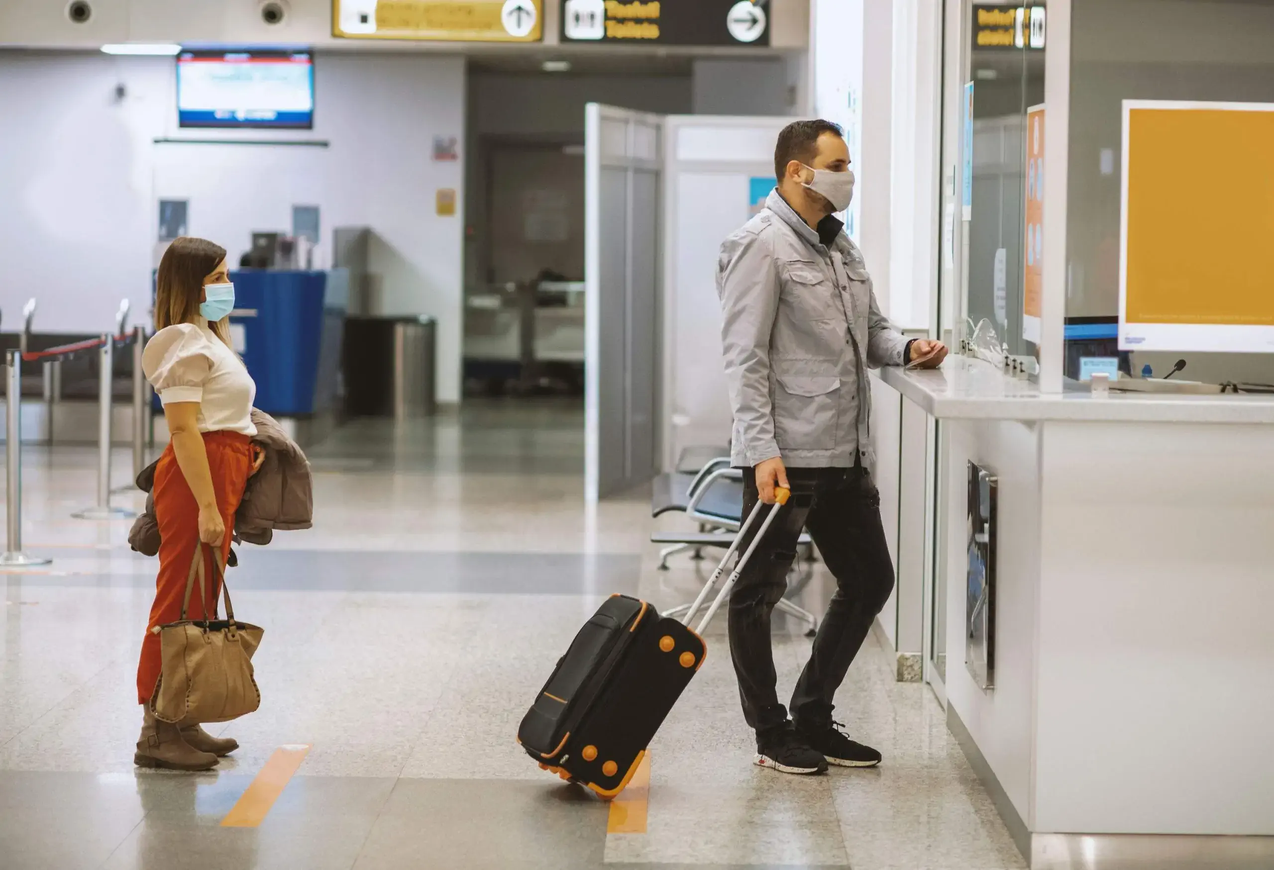 Passengers wearing face masks checking in for their flight at an airport.