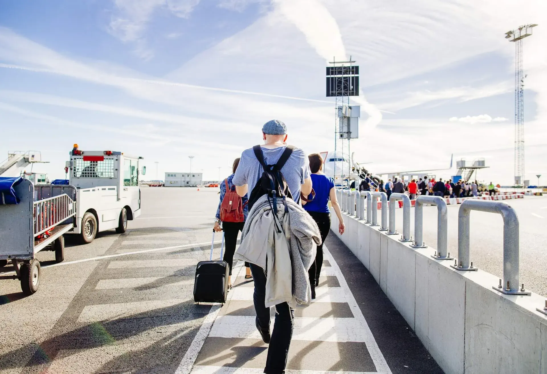 Rear view of friends moving towards airplane at terminal.