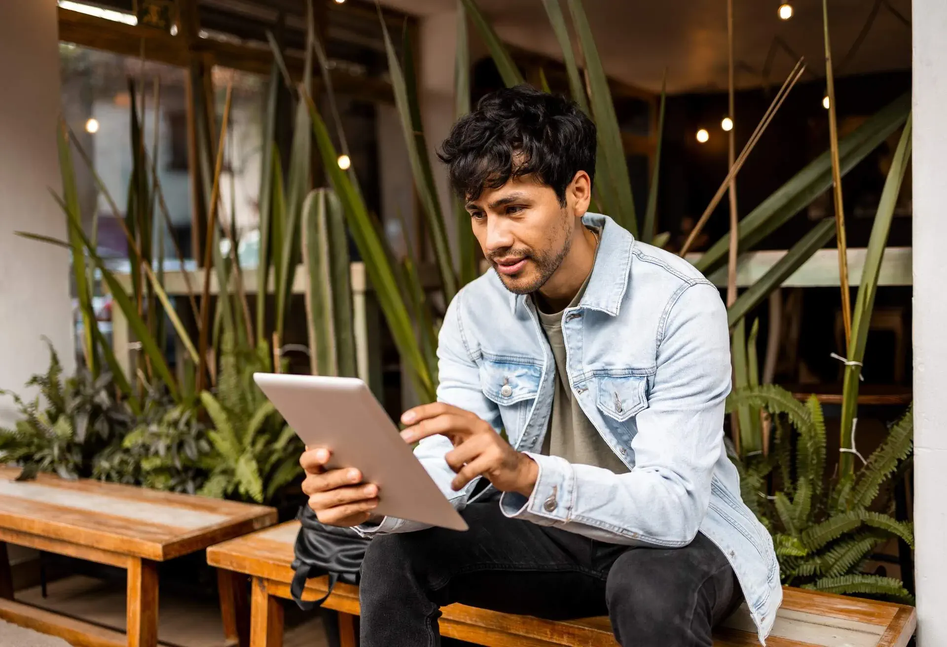 Man sat in a cafe looking at iPad device