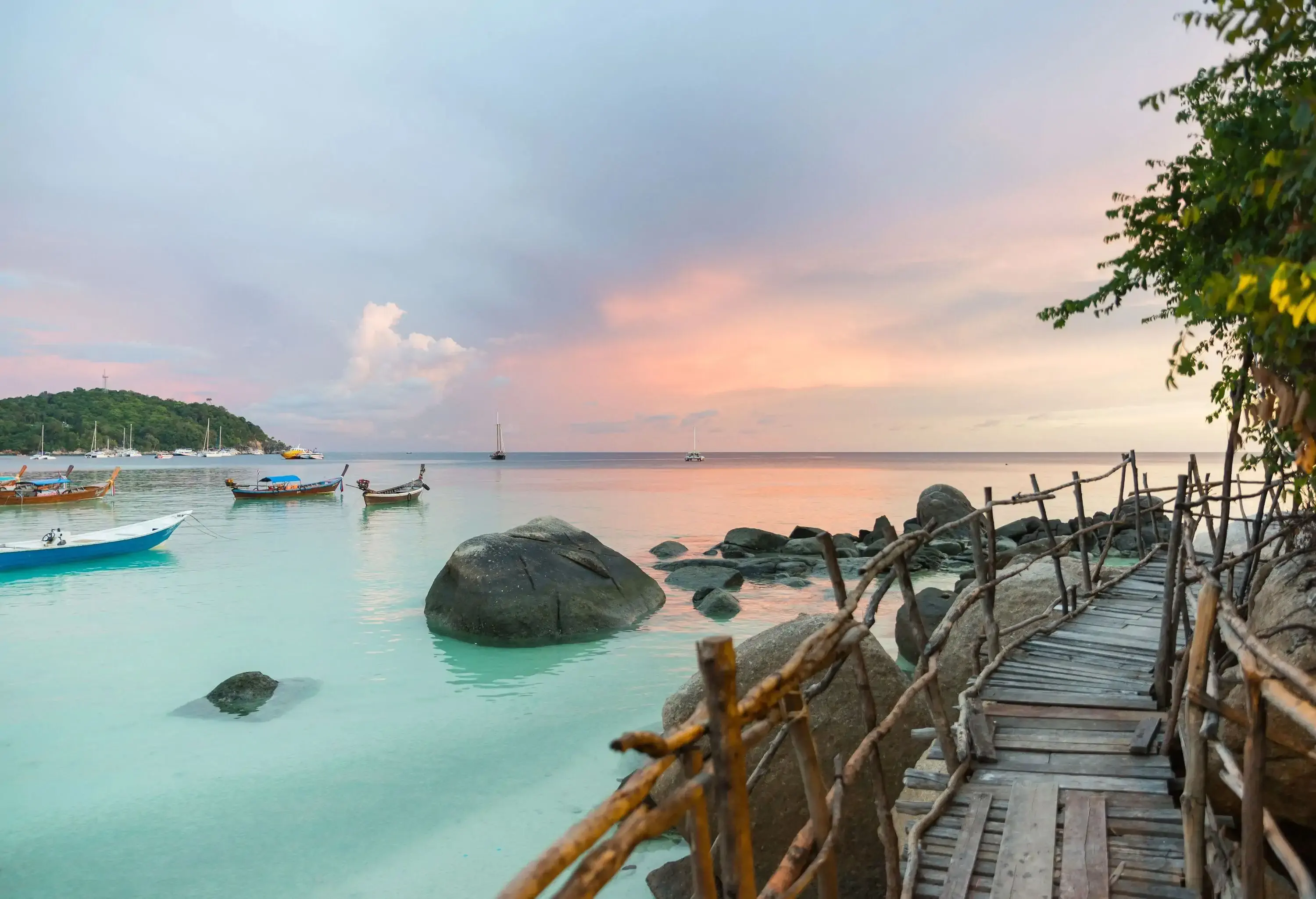 A quaint wooden bridge stretches over the water, with boats gently bobbing nearby.