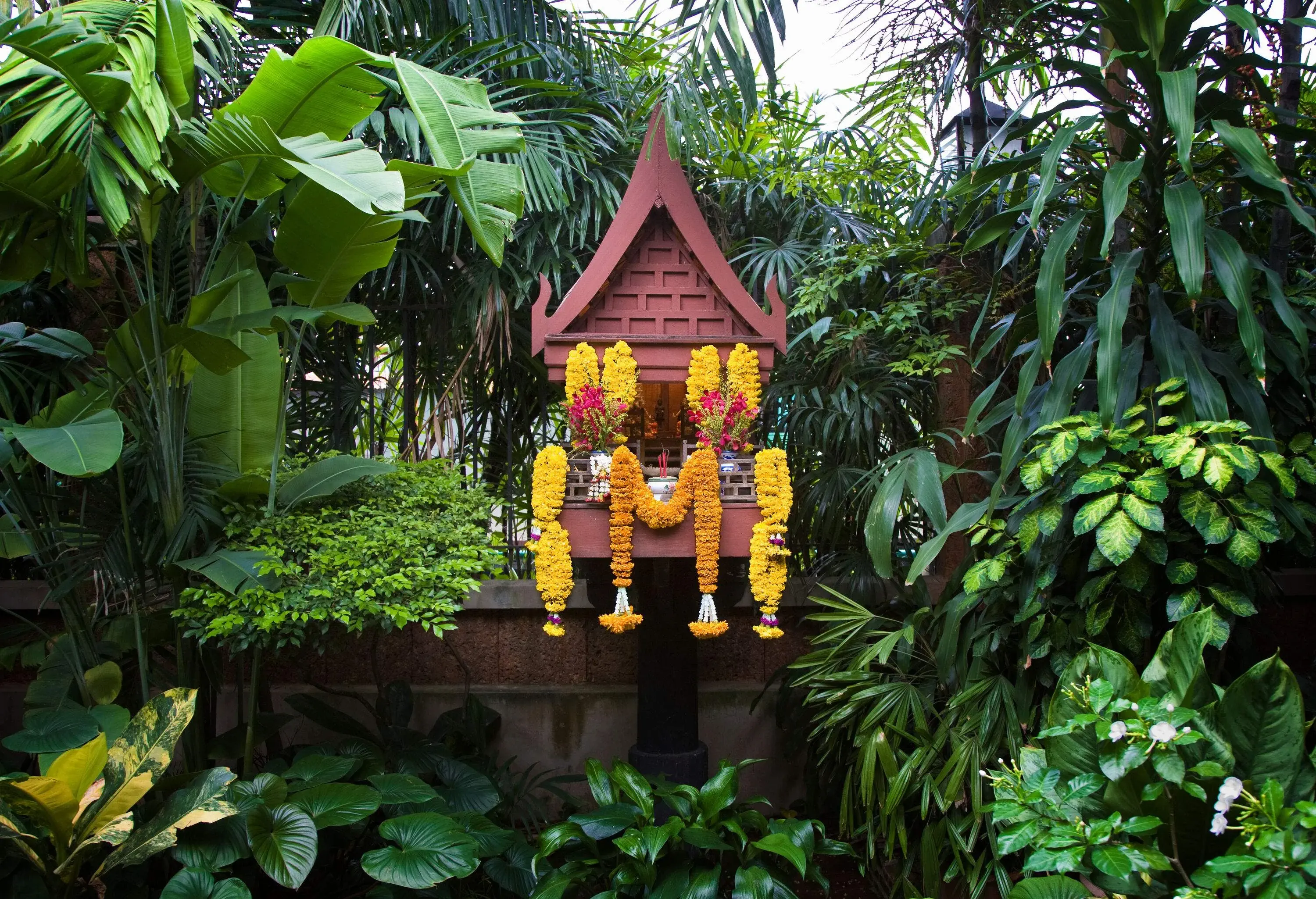 Yellow flower offerings hanged at the Spirit House in the gardens.