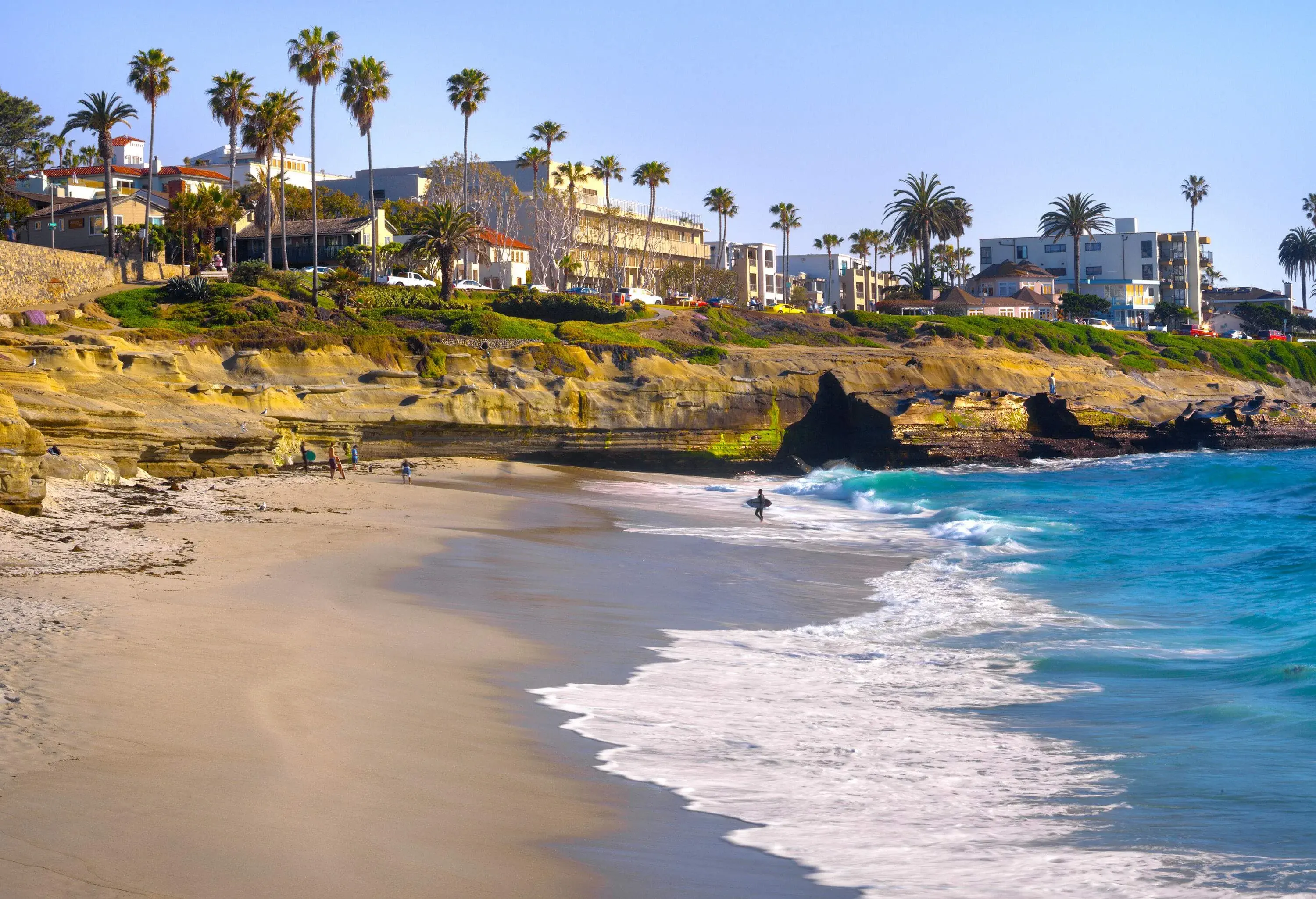 A coastal town featuring a lush and sandy shore, embraced by the sparkling turquoise sea.