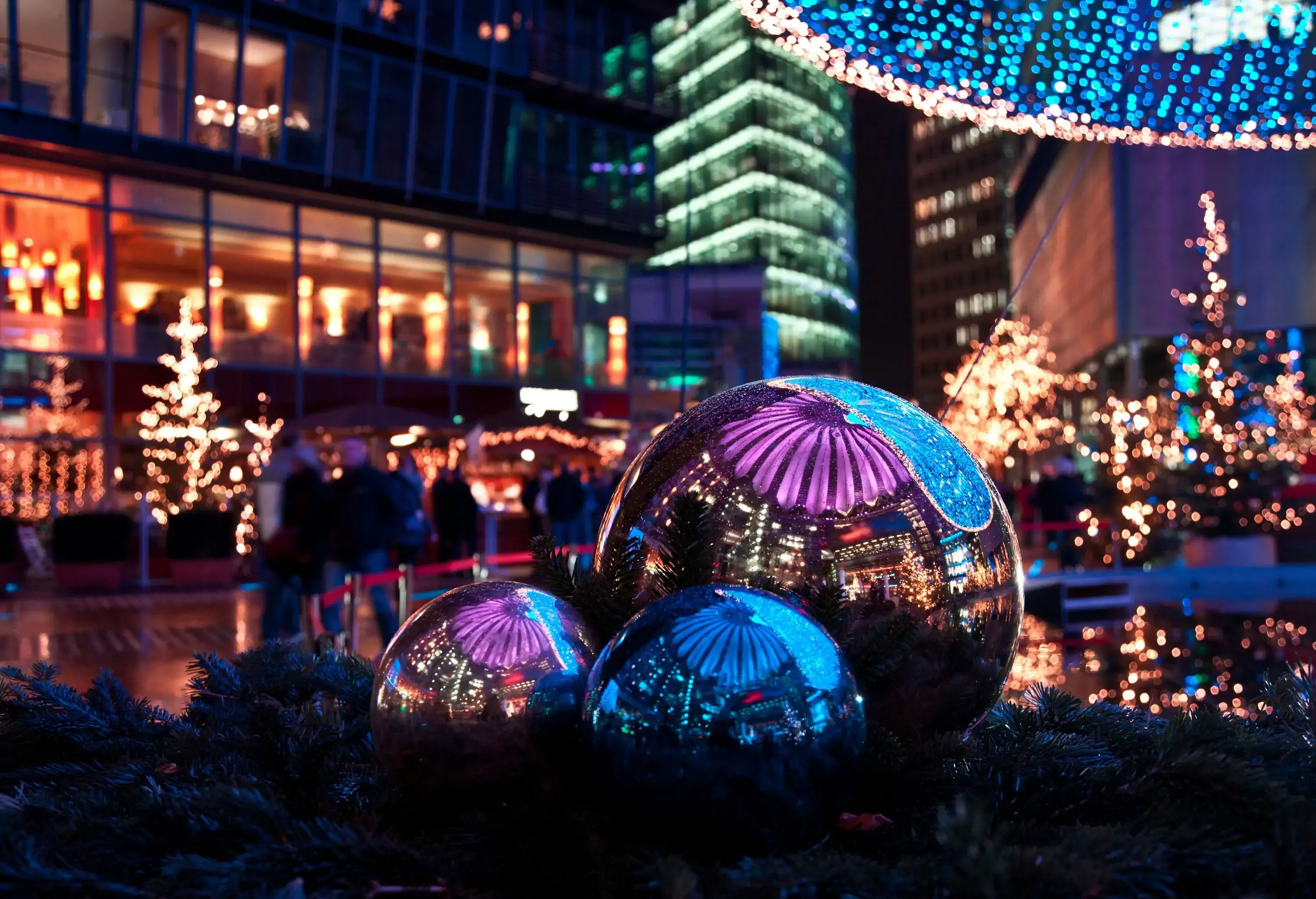 christmas market decorated with lights in the Sony Center of Berlin, reflected in the metal baubles