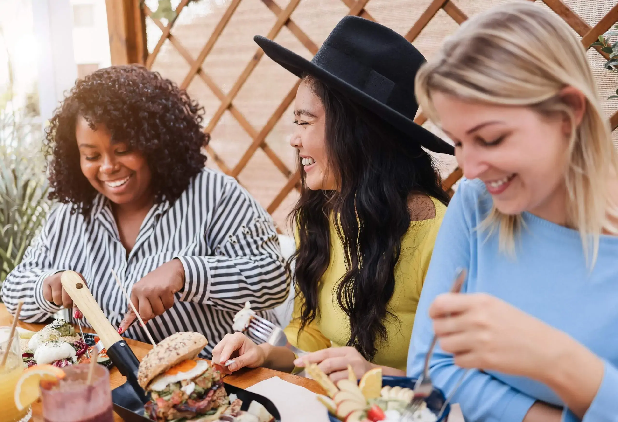 Three joyful multiracial friends relish an outdoor breakfast, basking in each other's company and happiness.