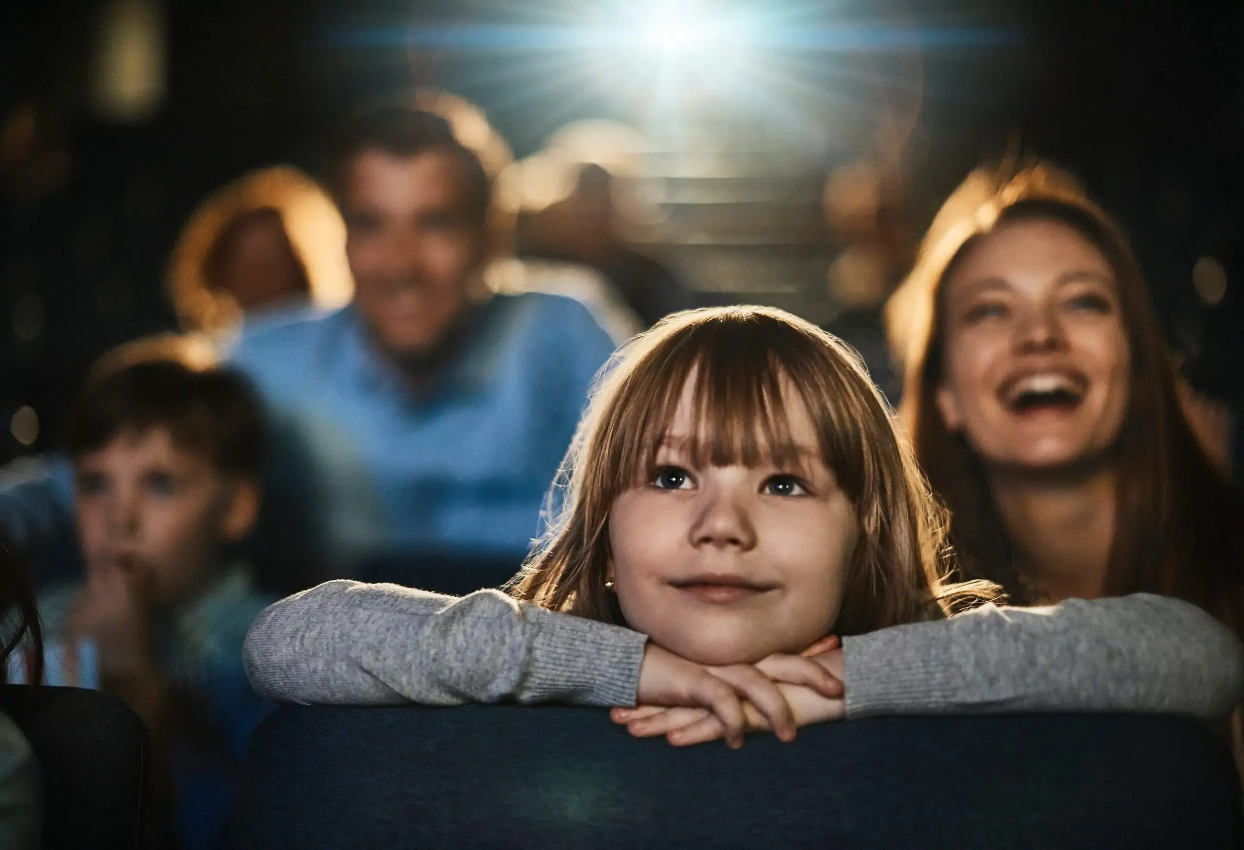 Closeup of a young girl with her family inside the cinema.