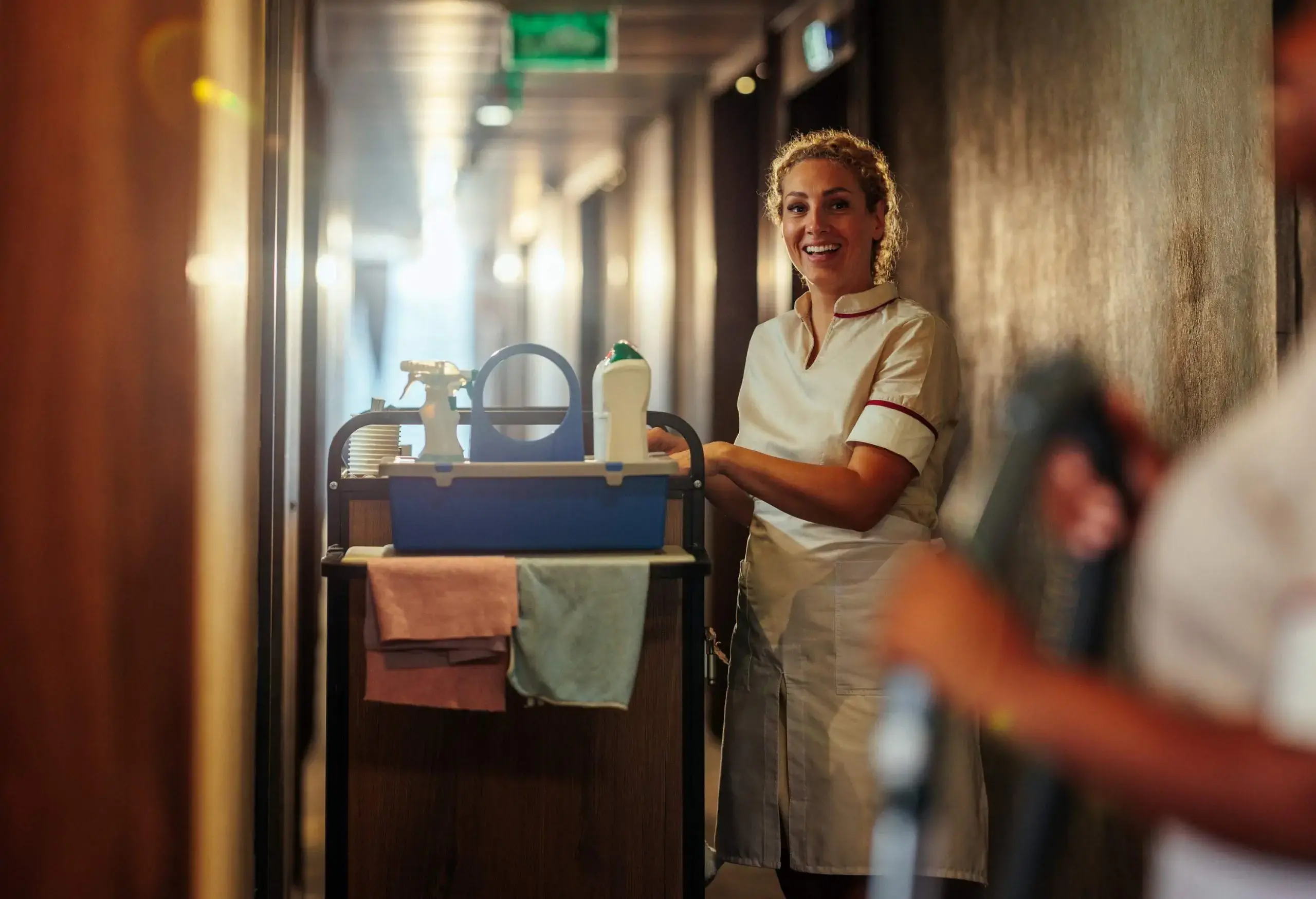 Maid laughing while talking to coworker in the hall.
