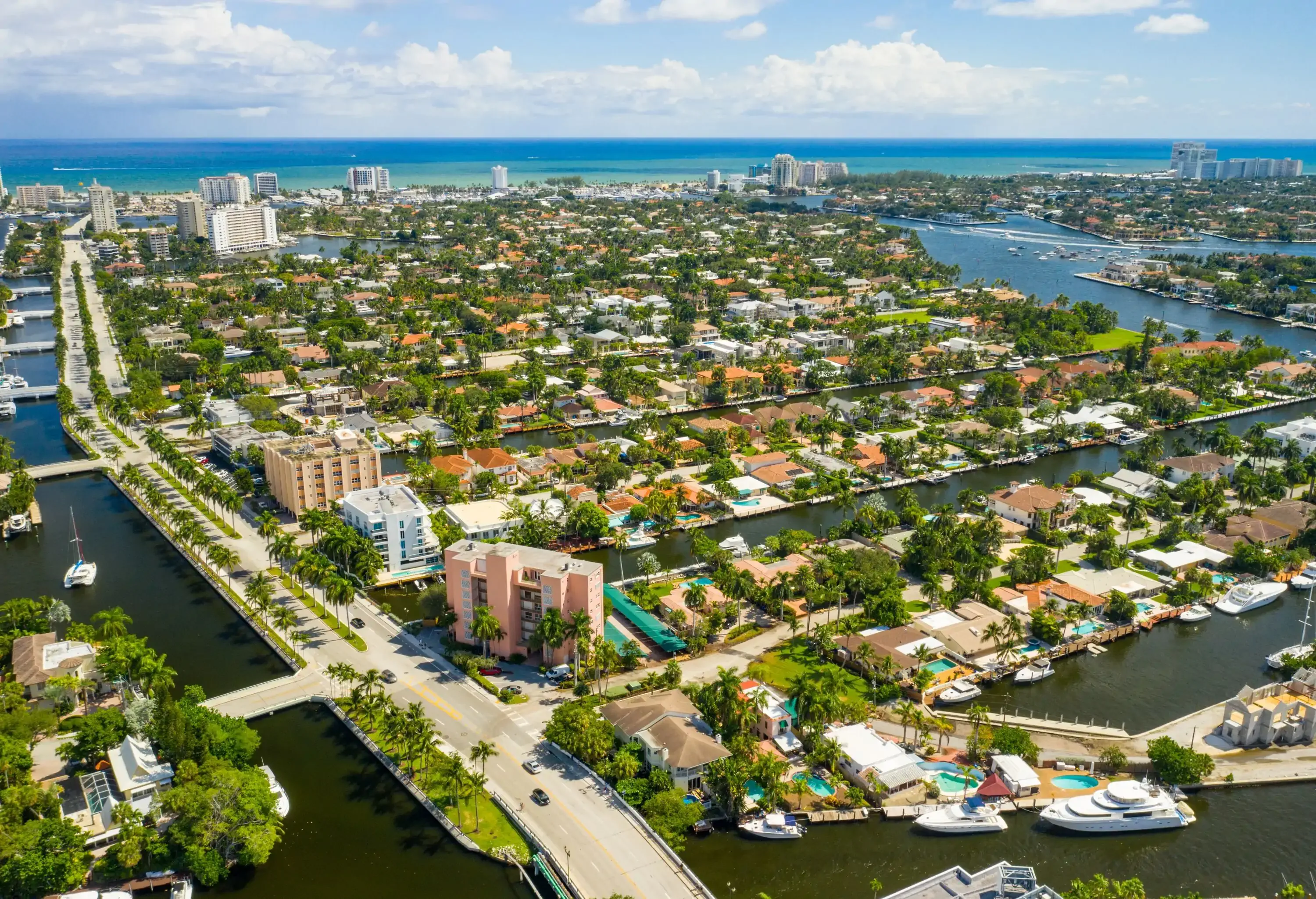 A tree-lined street along a residential neighbourhood with waterfront houses across the water canals.