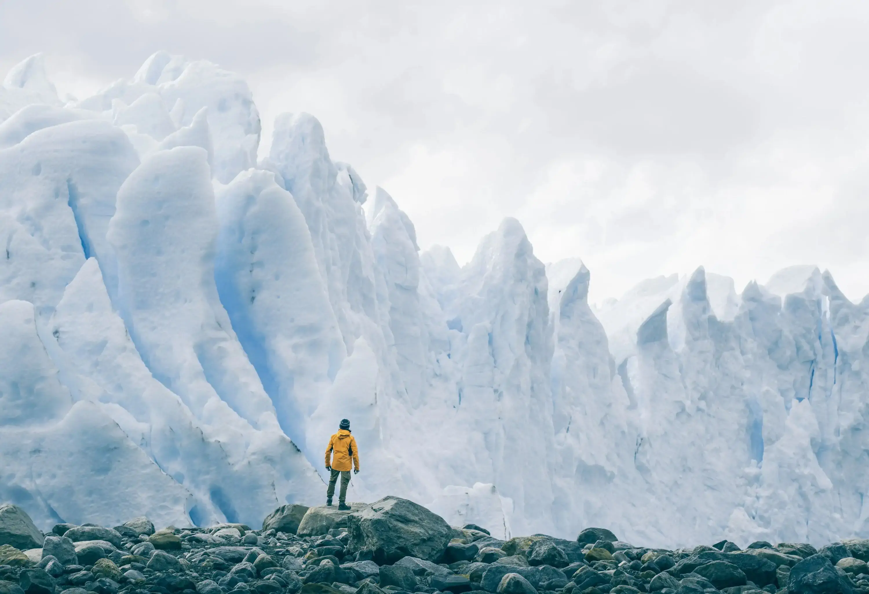 A lone figure gazes in awe at the majestic expanse of the Perito Moreno glacier, standing at the bottom and marvelling at its colossal size, immensity, and awe-inspiring beauty.