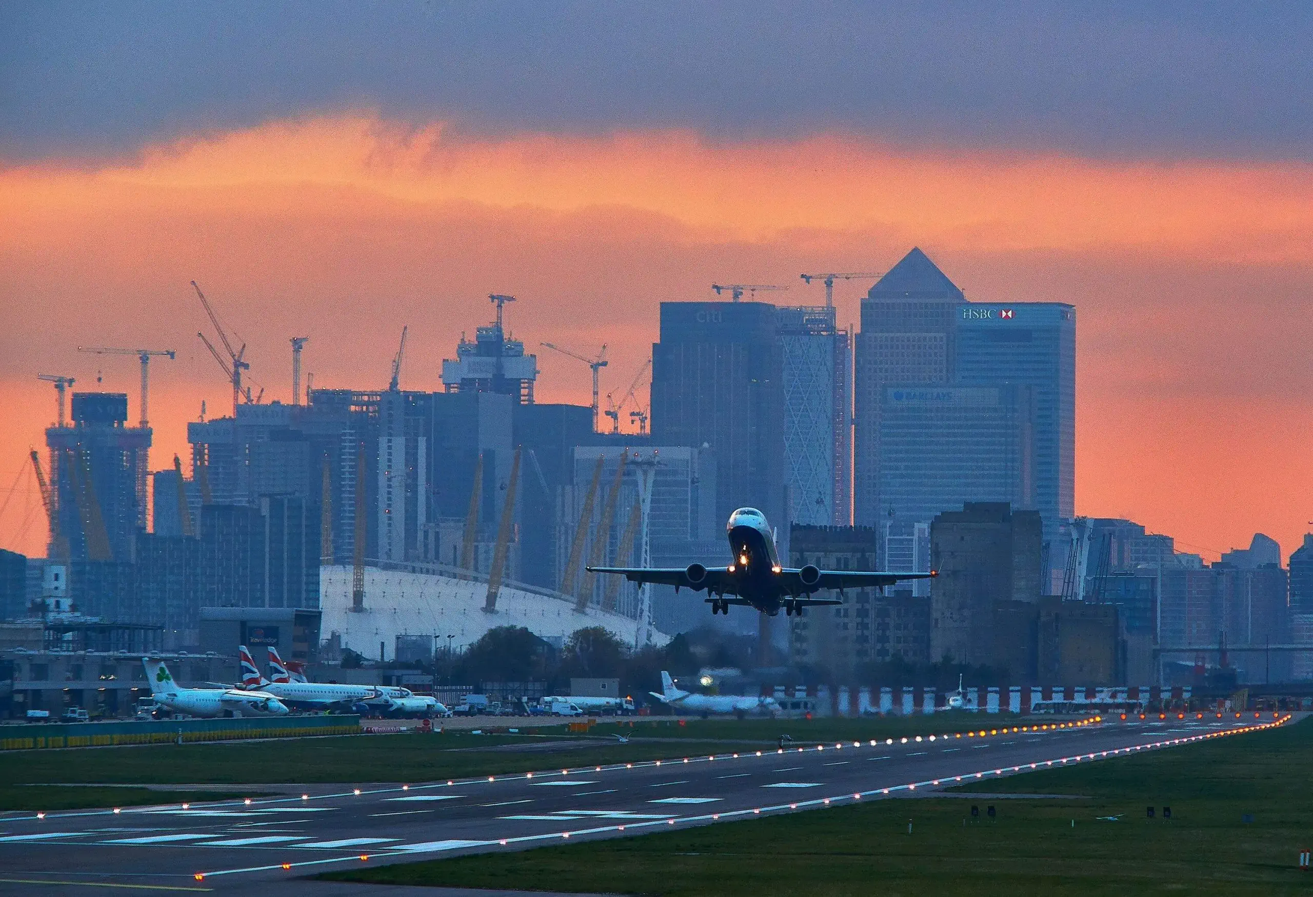 Passenger Aircraft taking off with the buildings of Canary Wharf in the distance.