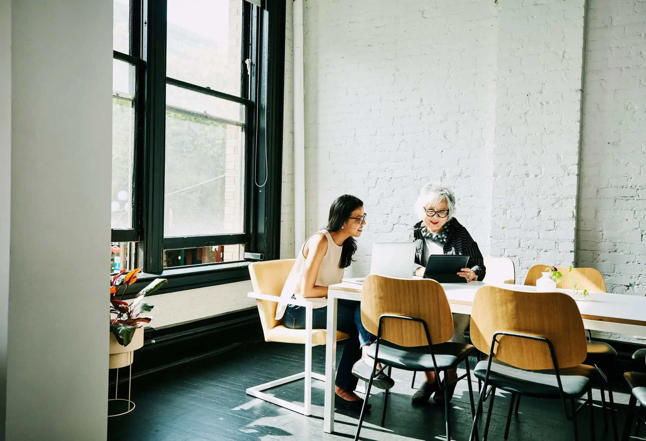 Two female workmates discussing a matter at the conference table.
