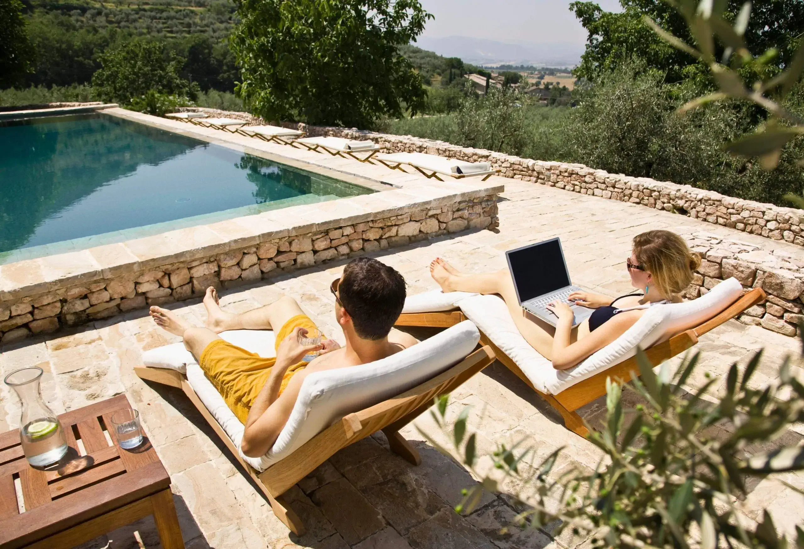 Couple working on laptop by the pool