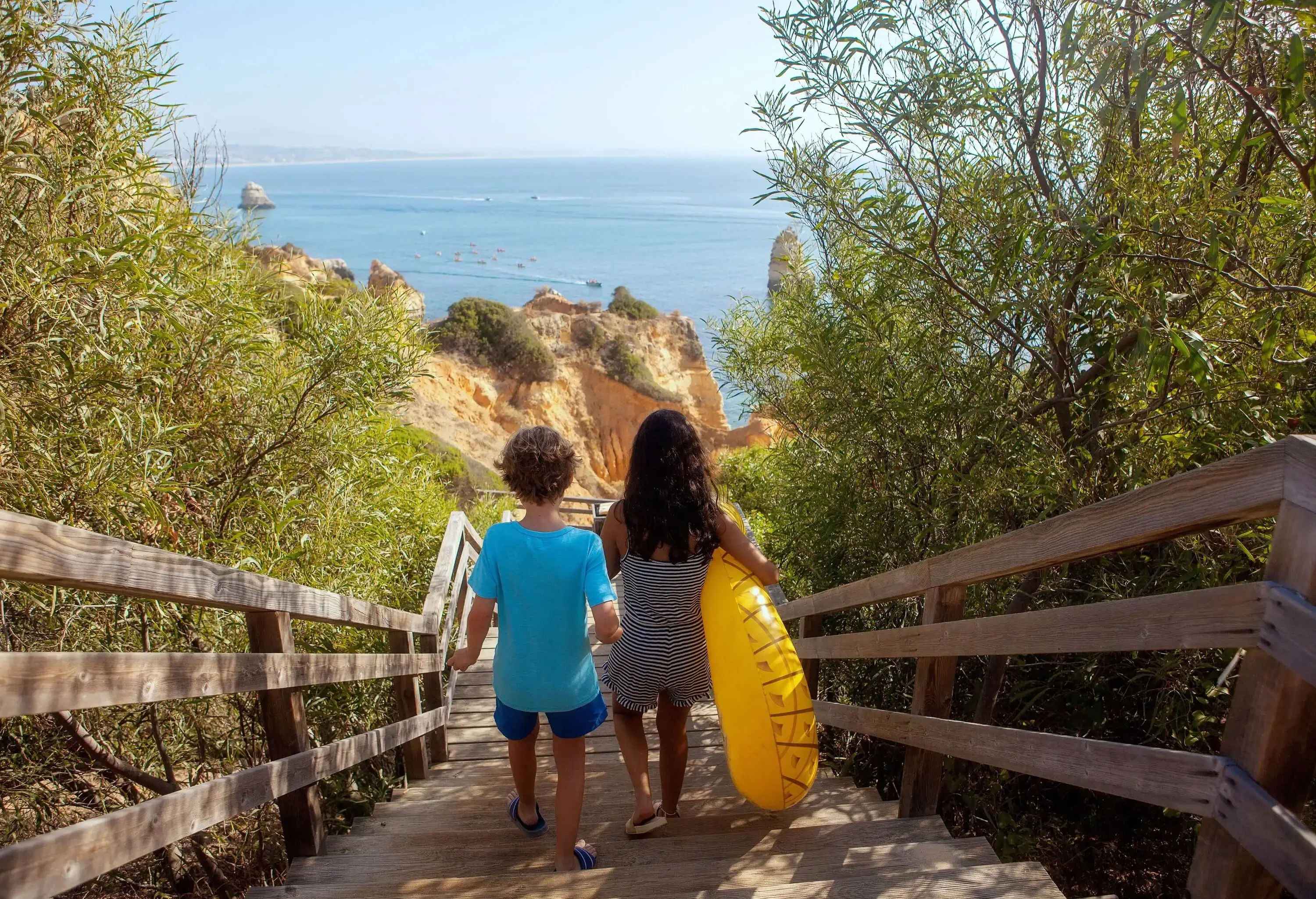 Two children making their way down the wooden stairs to the beach.