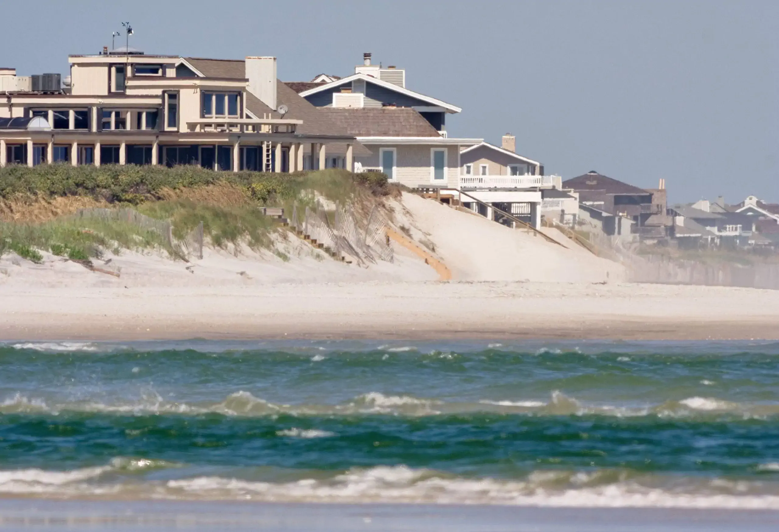 Townhomes lined up on elevated land alongside the sea.