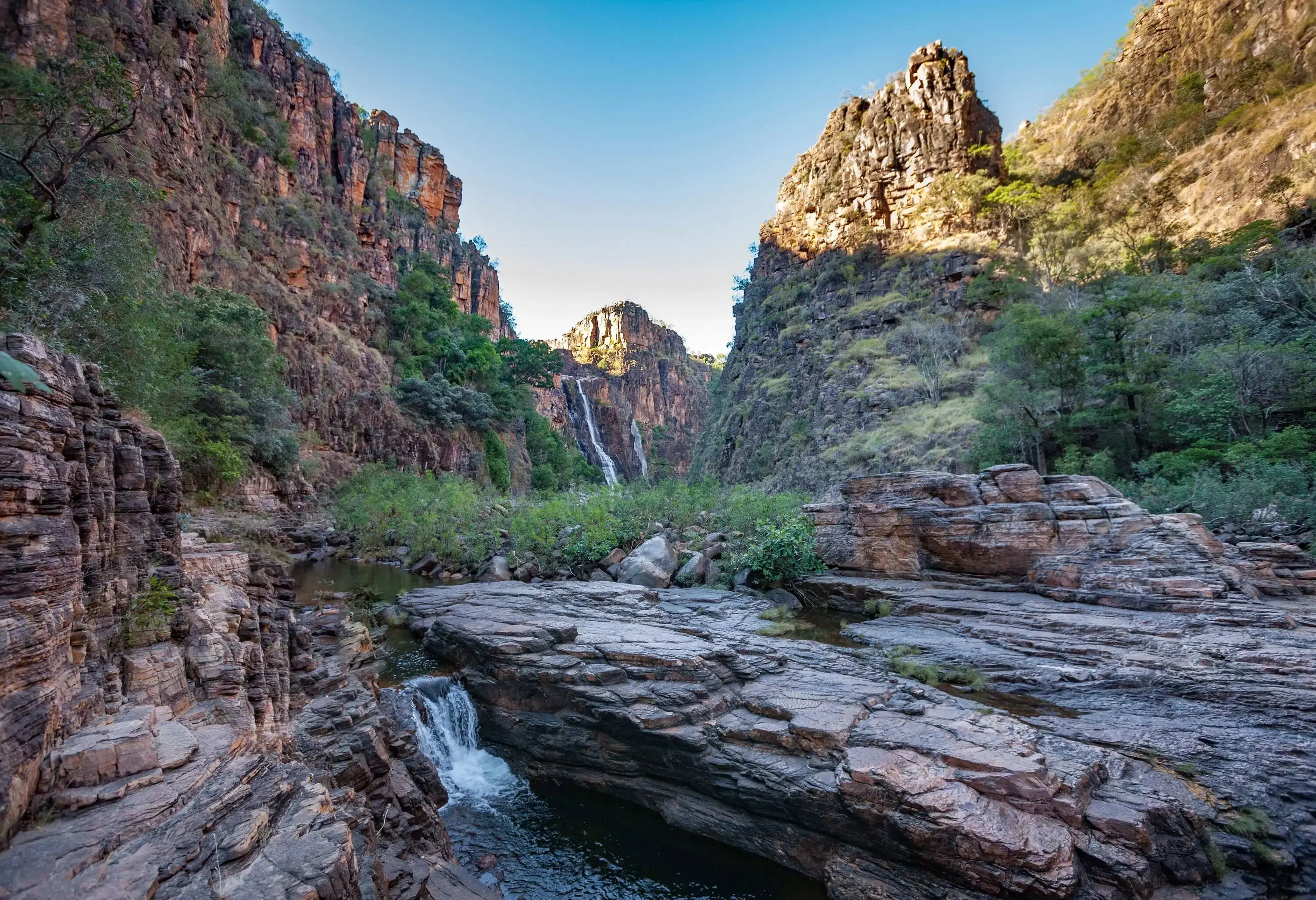 Breathtaking gorge nestled between rocky mountains, with a serene stream of water flowing through its centre.