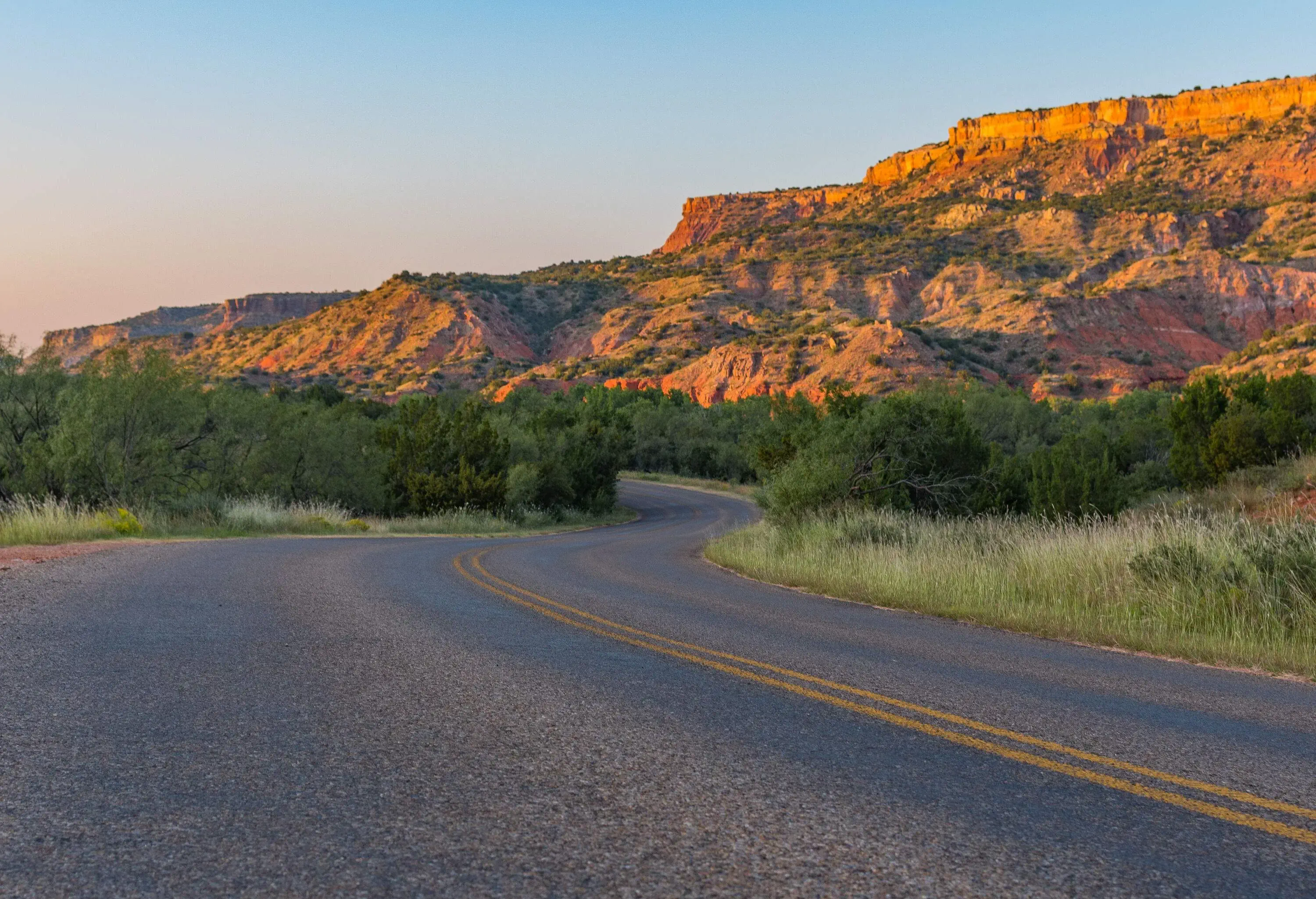 A winding roadway surrounded by sandstone hills and mountains.