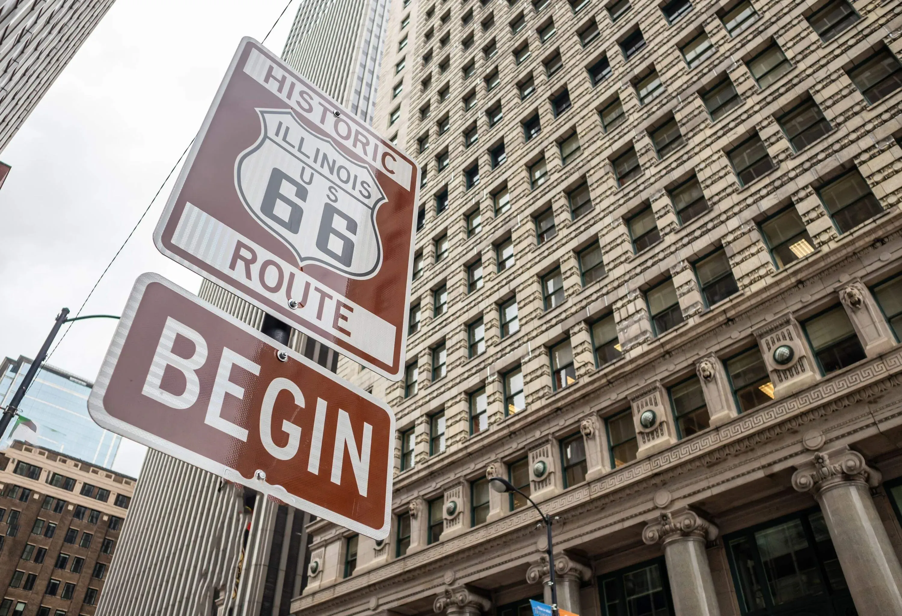 Route 66 Illinois Begin road sign at Chicago city downtown. Buildings facade background. Route 66, mother road, the classic historic roadtrip in USA
