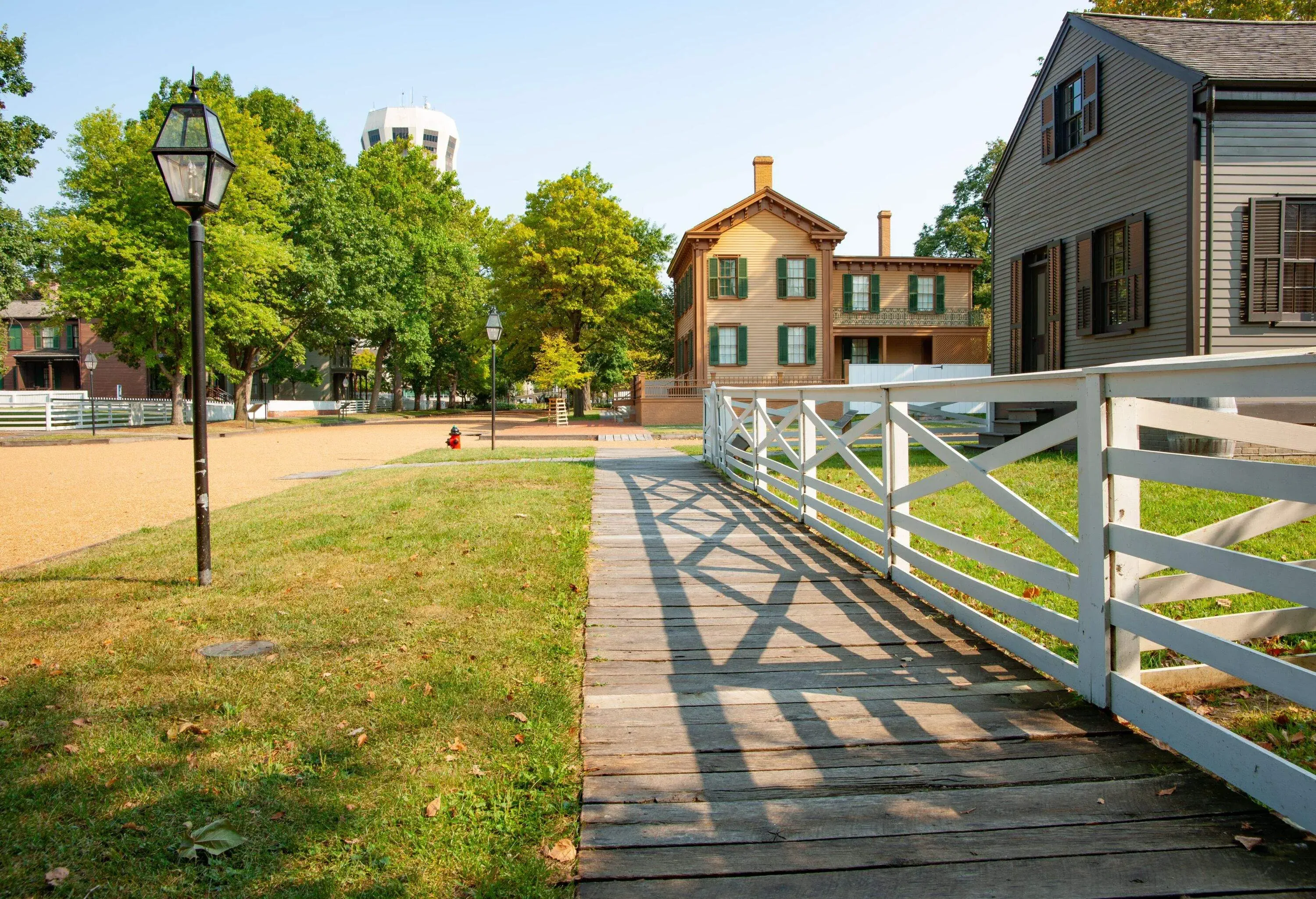Wooden footpath leading along street with white fence and shadows in New Salem, Springfield, Illinois, USA.